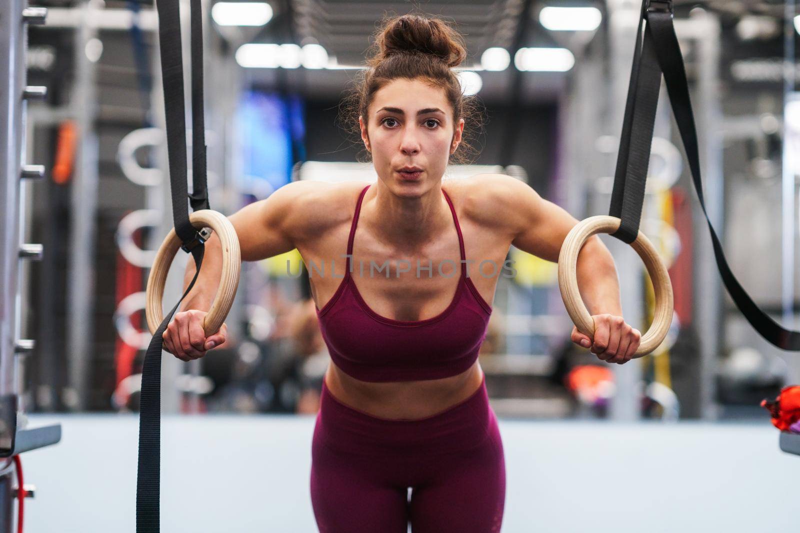 Athletic woman doing some pull up exercises in the gymnastic rings in a gym