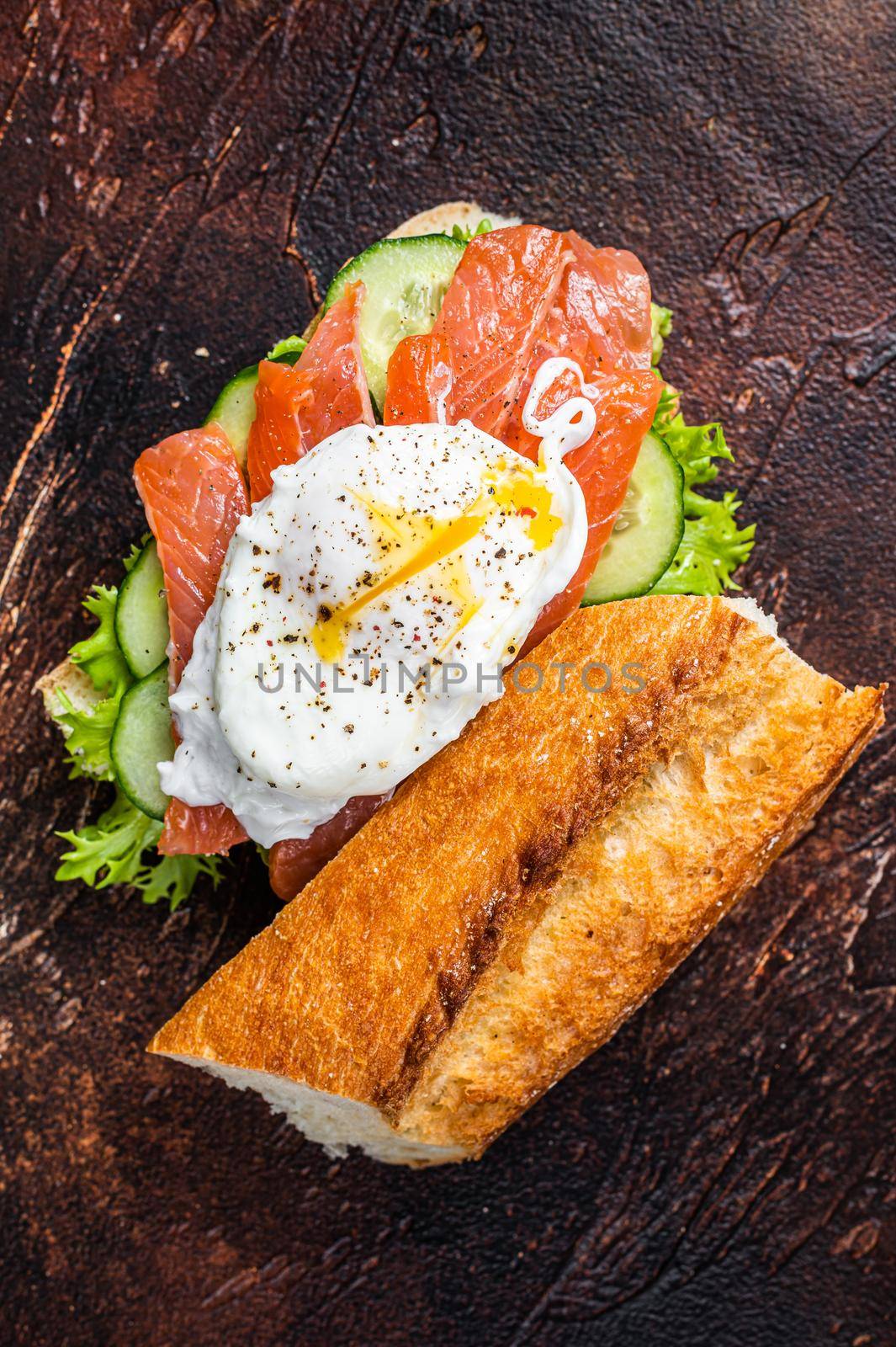 Poached egg with smoked salmon and avocado on toast. Dark background. Top view.