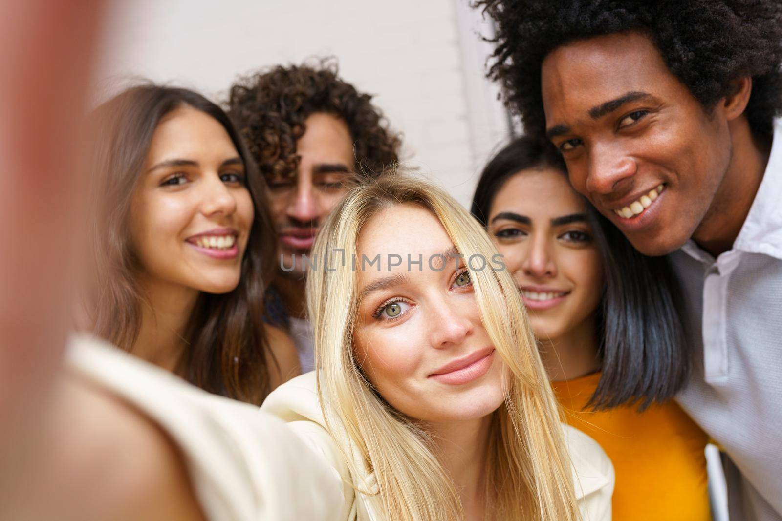 Multi-ethnic group of friends taking a selfie together while having fun outdoors. by javiindy