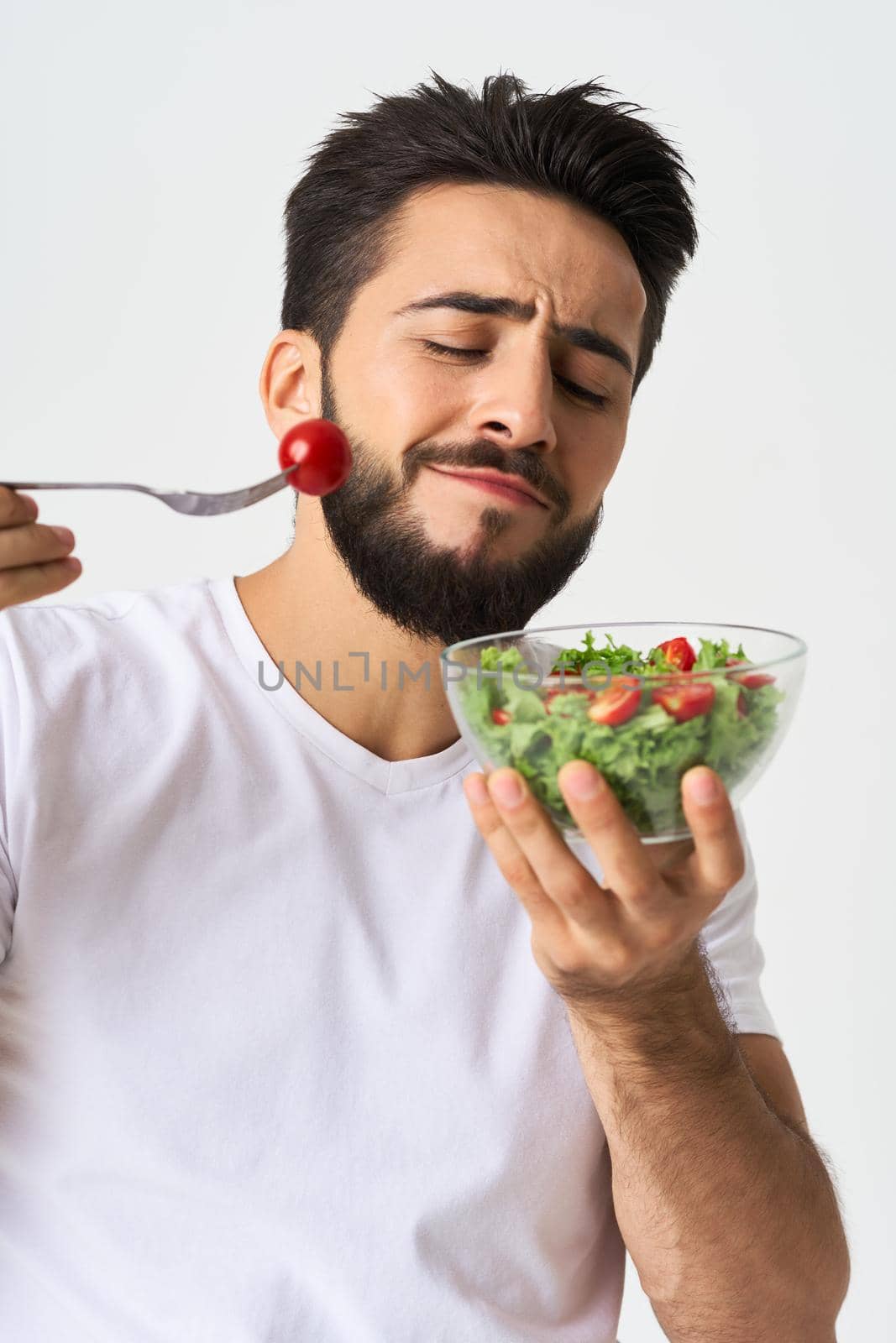 Cheerful man in a white T-shirt with a plate of light green and a healthy meal. High quality photo