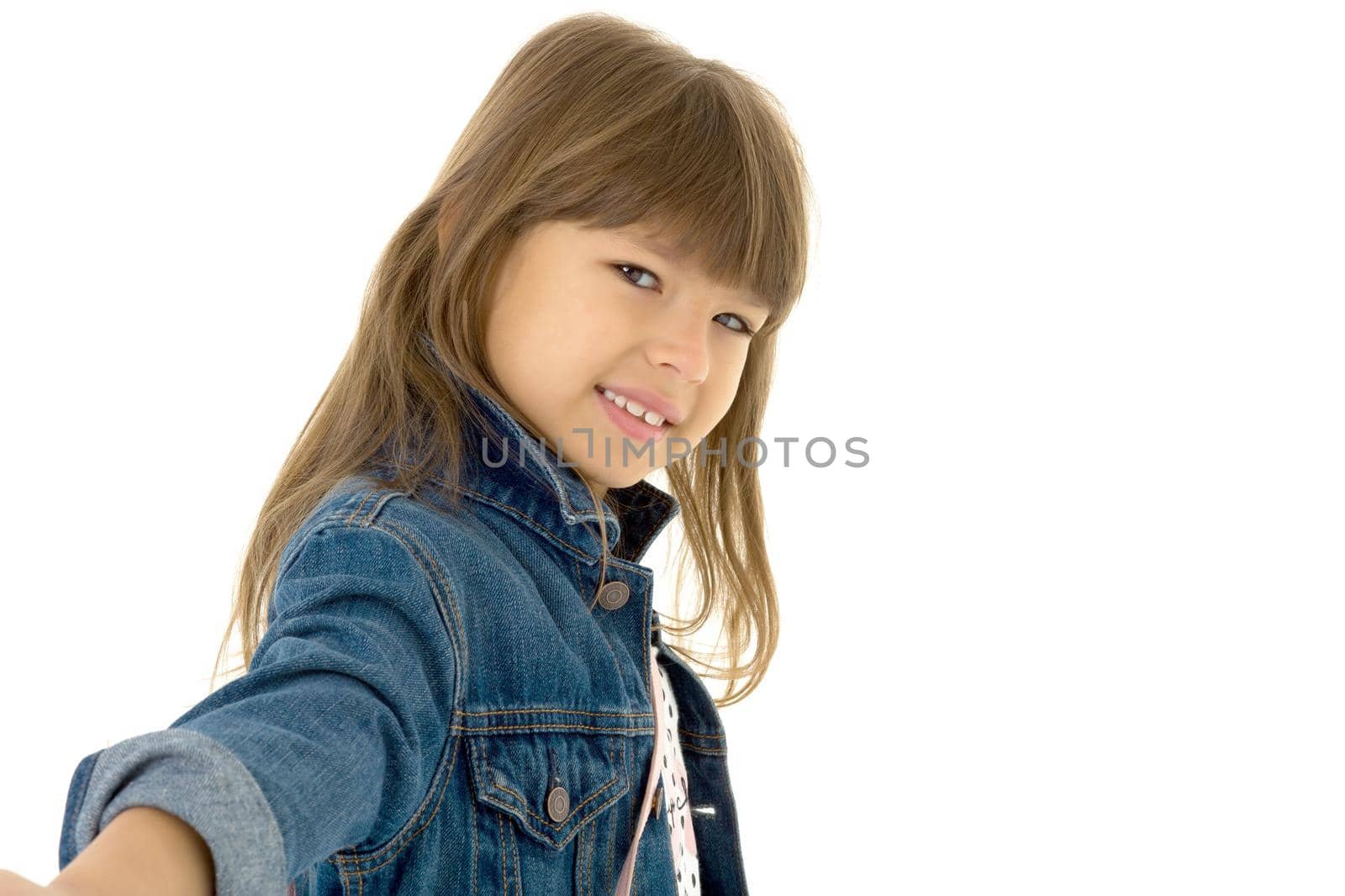 Portrait of happy girl in stylish outfit. Beautiful smiling brown eyed preteen girl wearing denim jacket posing against white background with crossbody shoulder bag