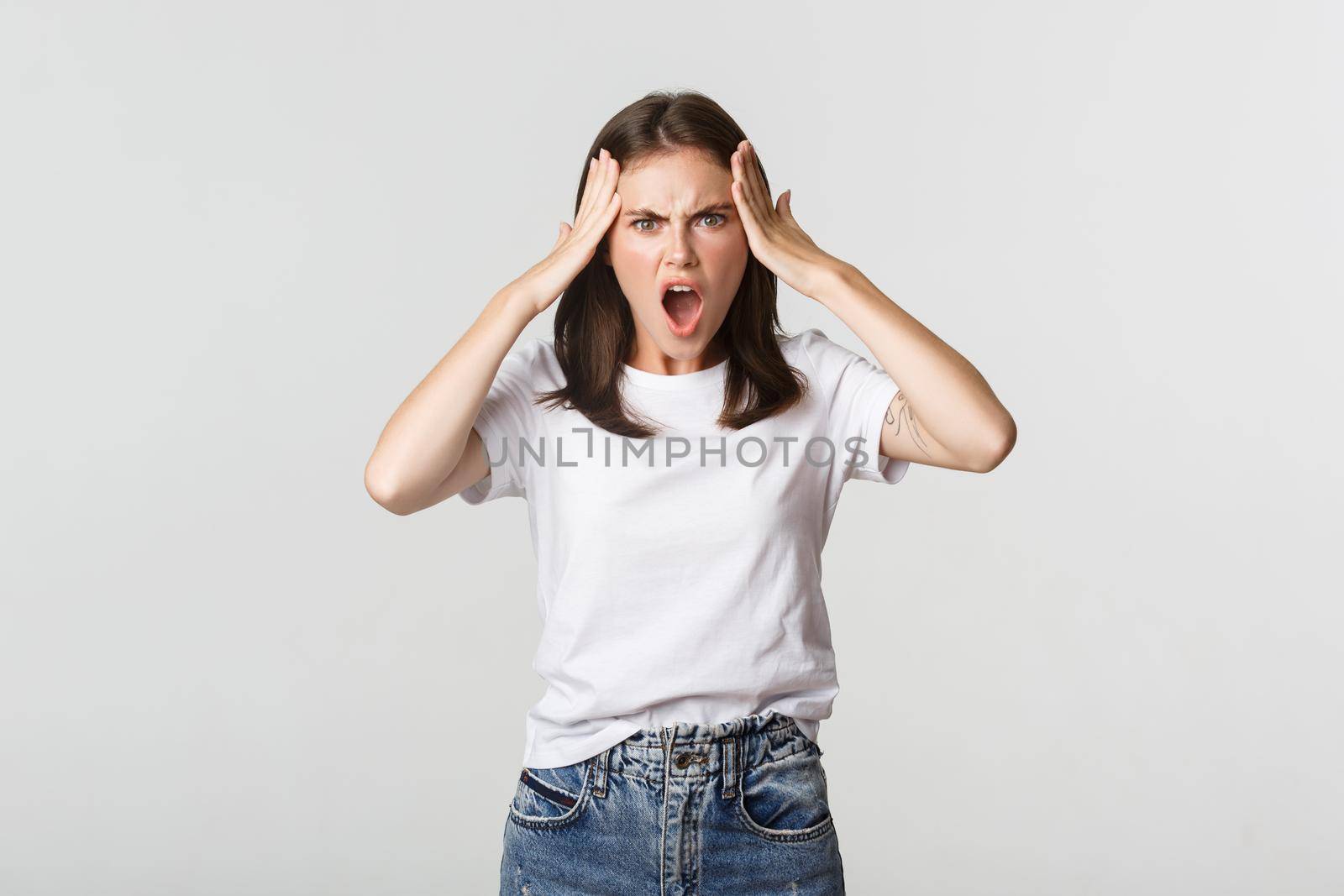 Mad and frustrated young woman looking shocked at camera.