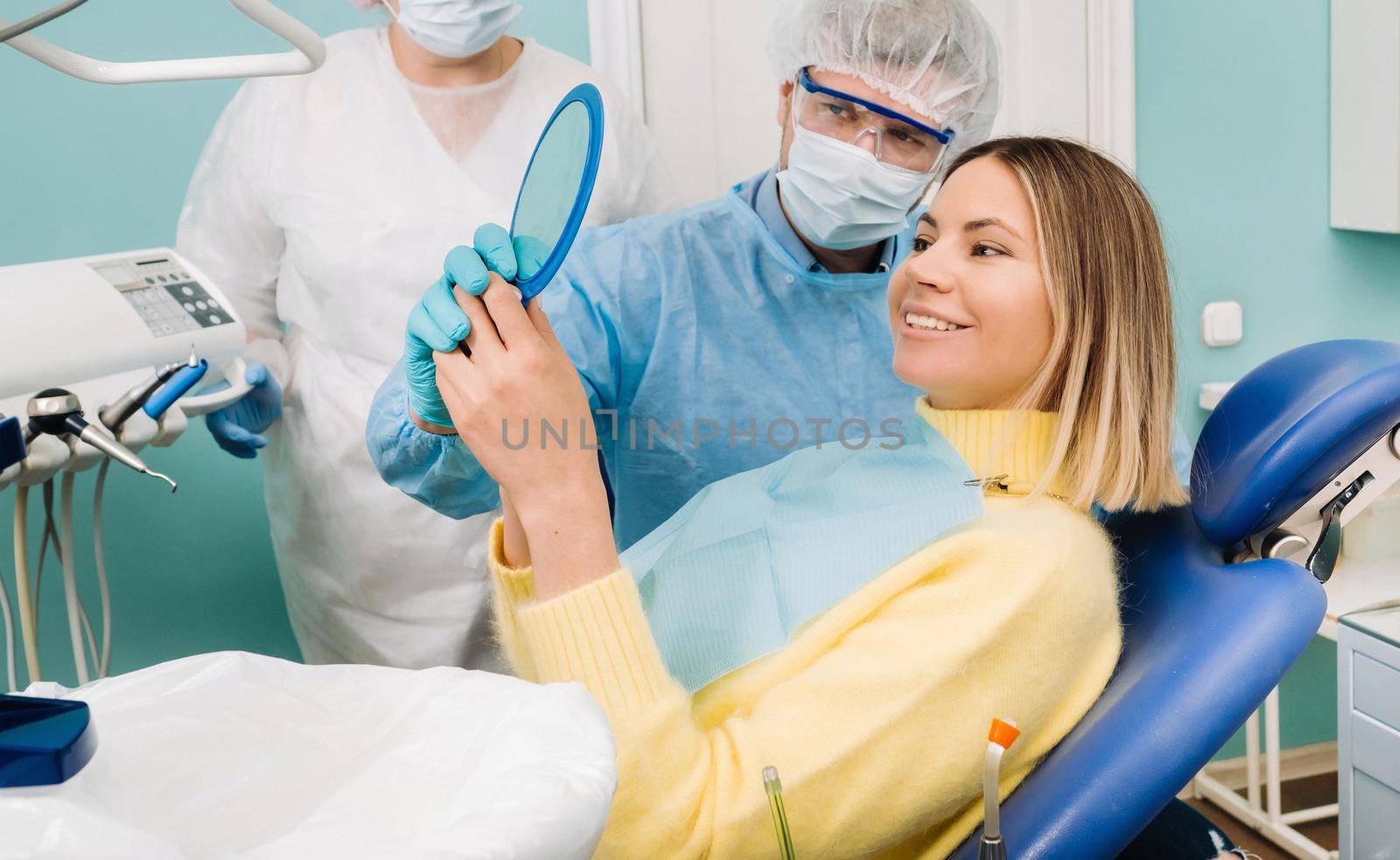 The dentist shows the client the results of his work in the mirror.