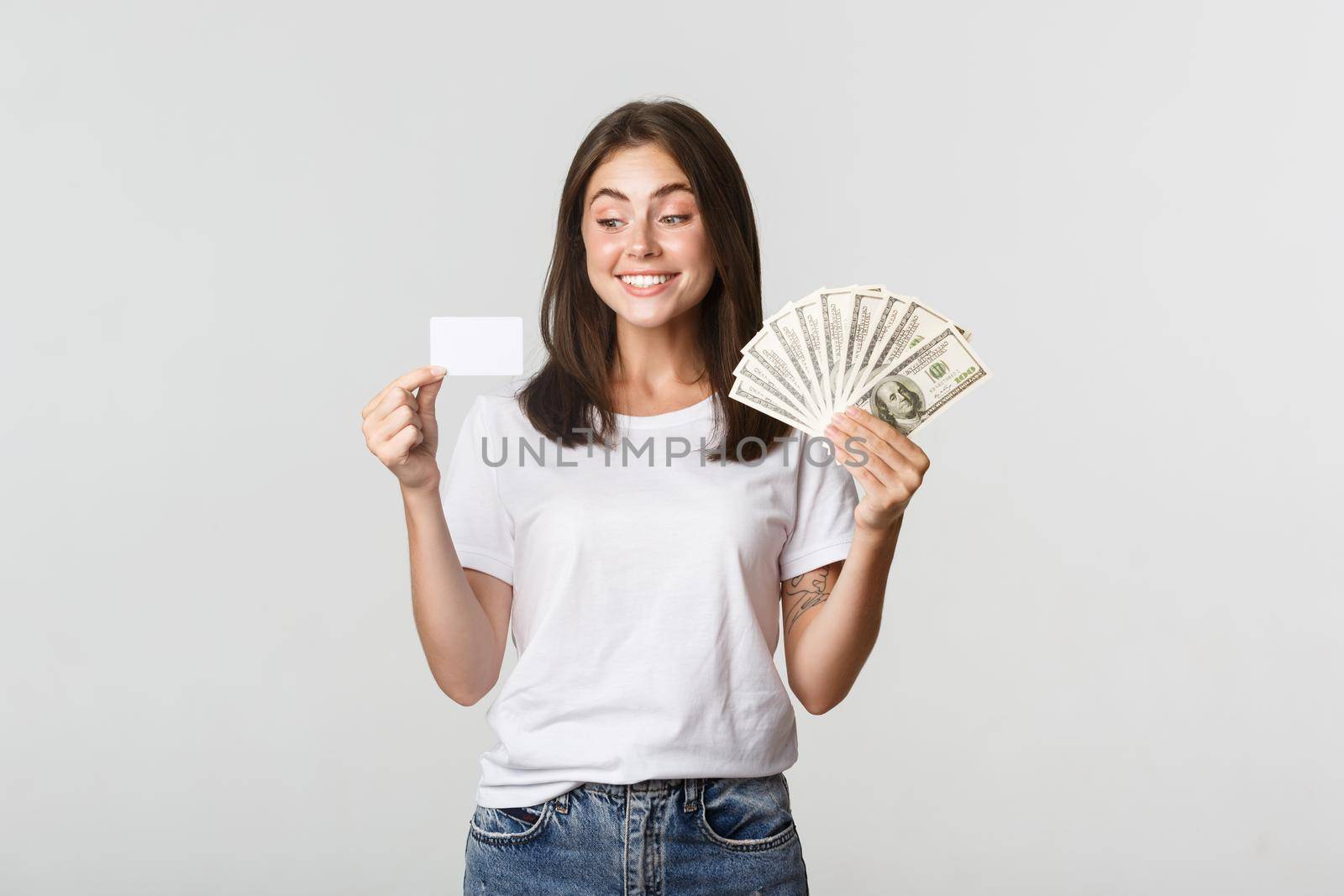 Portrait of excited smiling girl holding money and credit card, white background by Benzoix