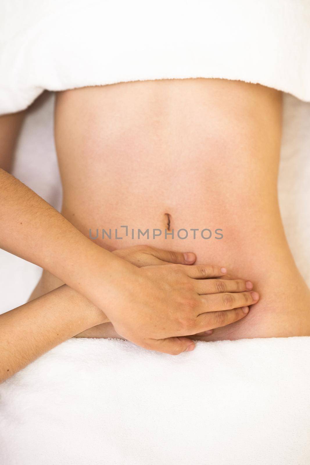 Top view of hands massaging female abdomen.Therapist applying pressure on belly