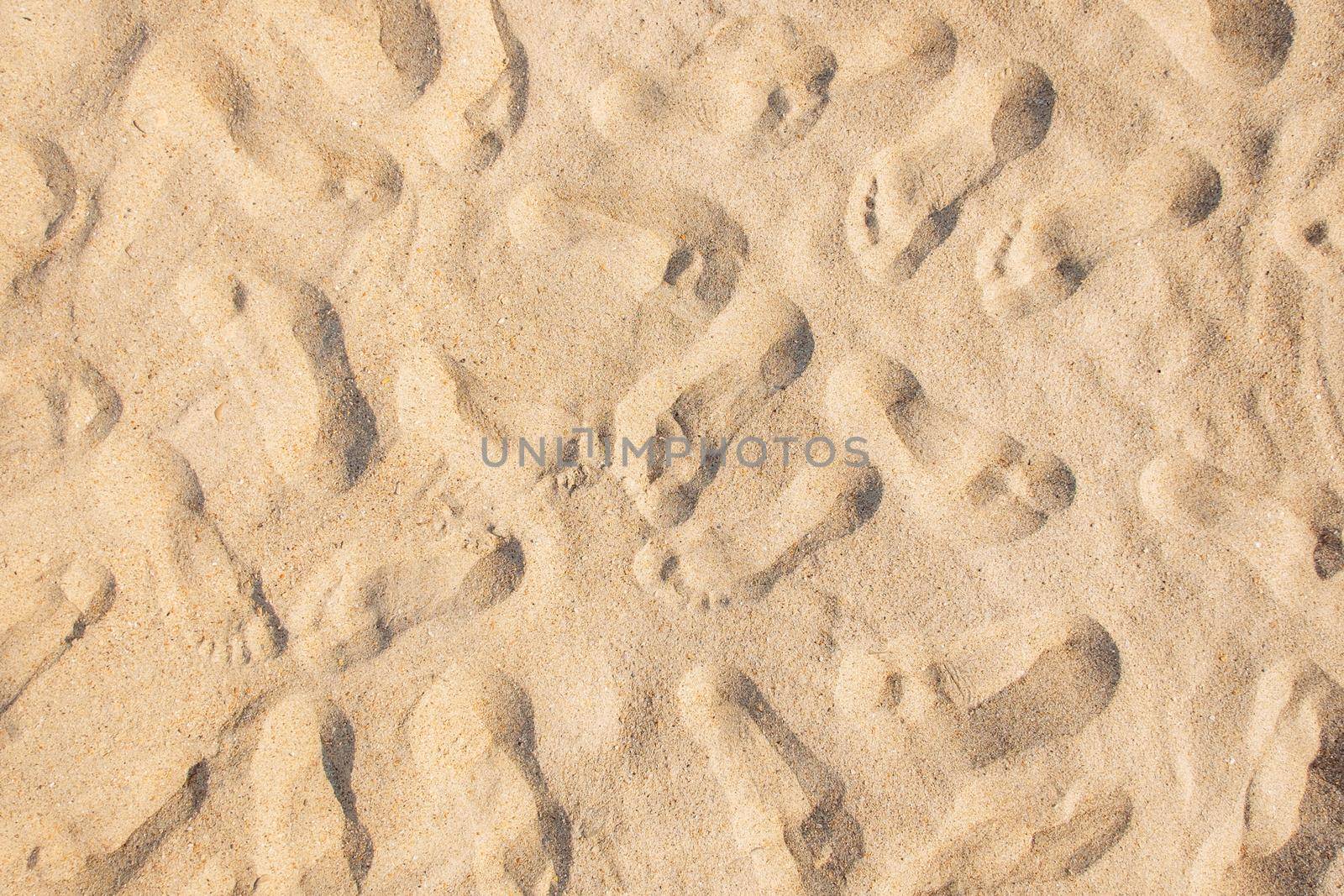 Many footprints on sandy beach background, texture, top view.