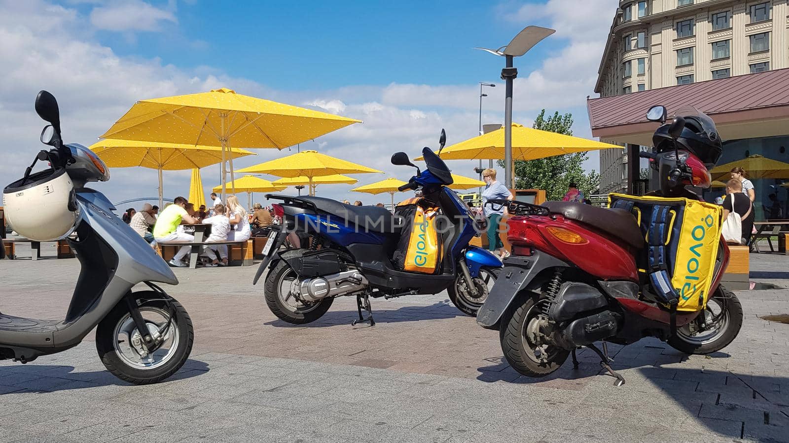 Ukraine, Kiev - August 29, 2020. Lot of parked mopeds with yellow bags with Glovo logo near McDonald's. Courier service that delivers goods ordered through a mobile application. Editorial photography. by Roshchyn