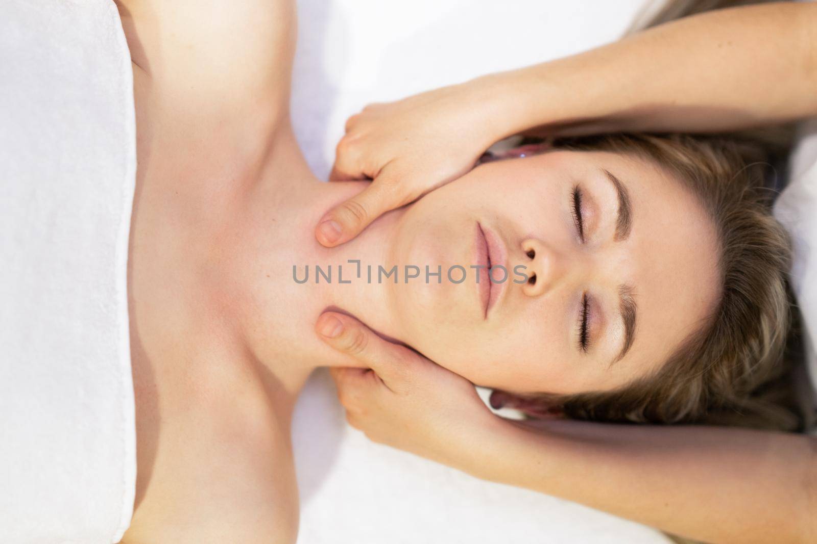 Young blond woman receiving a head massage in a spa center. by javiindy