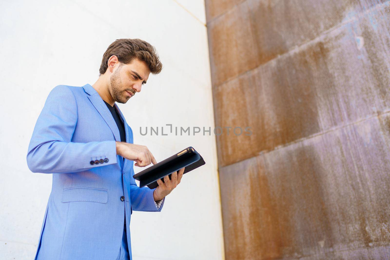 Young businessman using a digital tablet near an office building