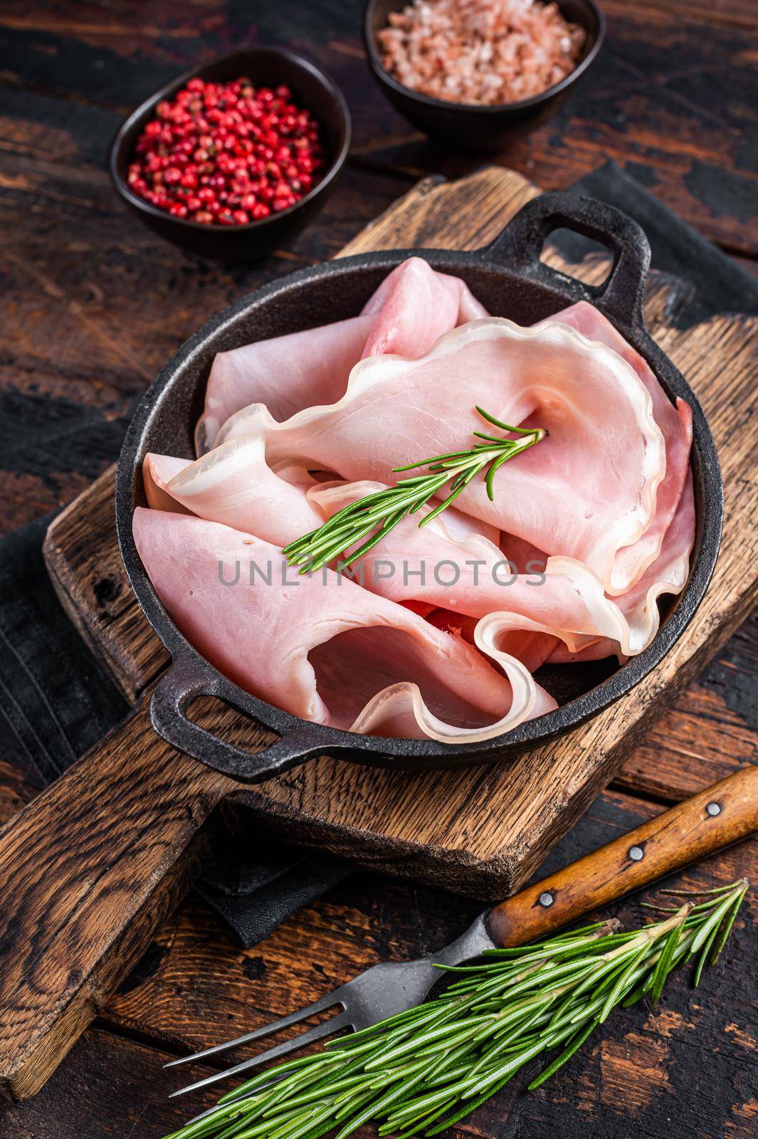 Prosciutto ham sliced in a pan. Dark wooden background. Top view.