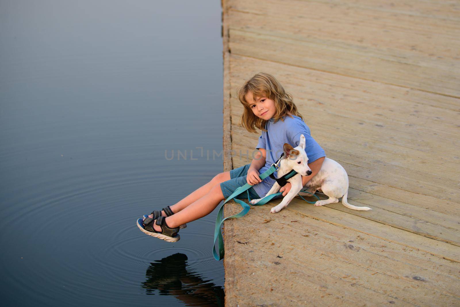 Child dreaming. Happy kid in the park with dog by the lake. by Tverdokhlib