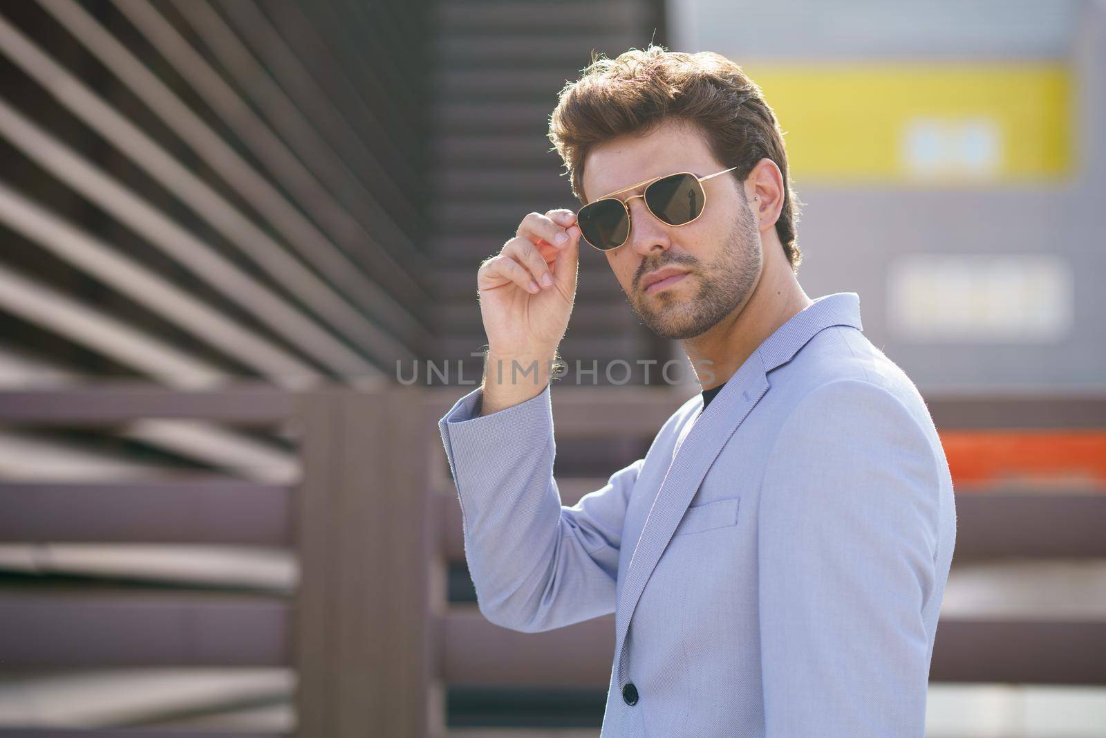 Young man, model of fashion, wearing sunglasses in urban background