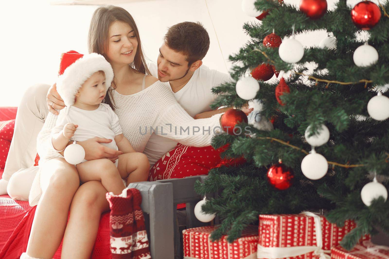 Mother in a white sweater. Family with christmas gifts. Child with parents in a christmas decorations.
