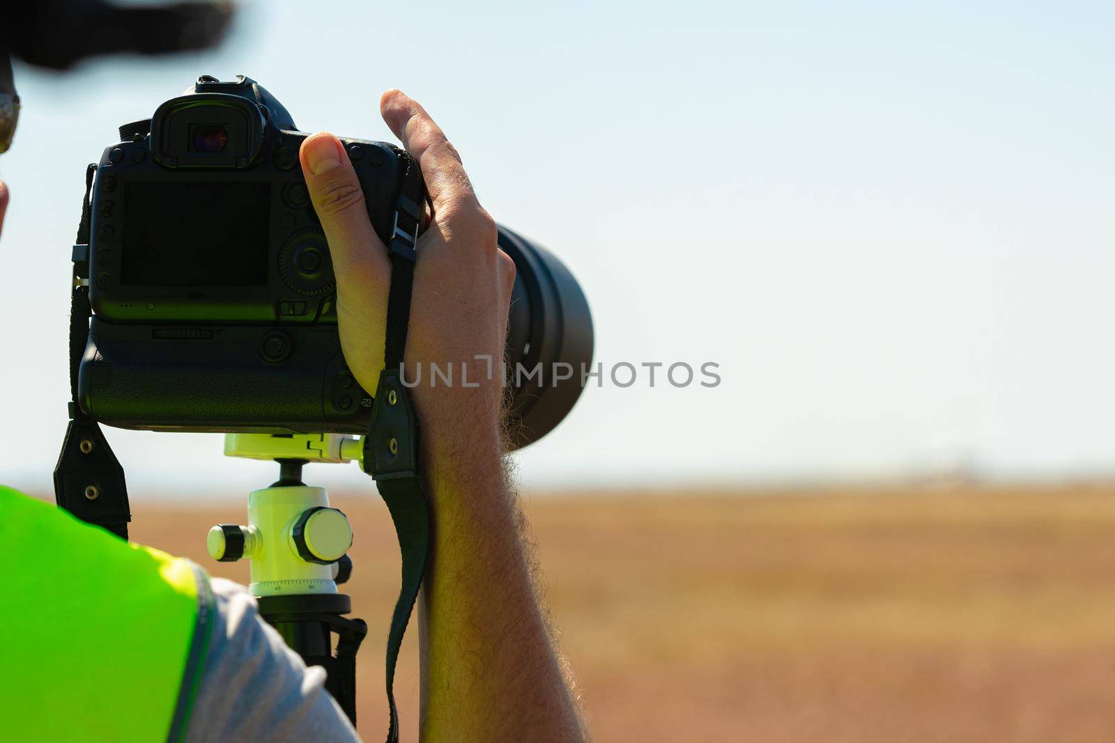 Man in yellow vest does plane spotting at the airport, close up