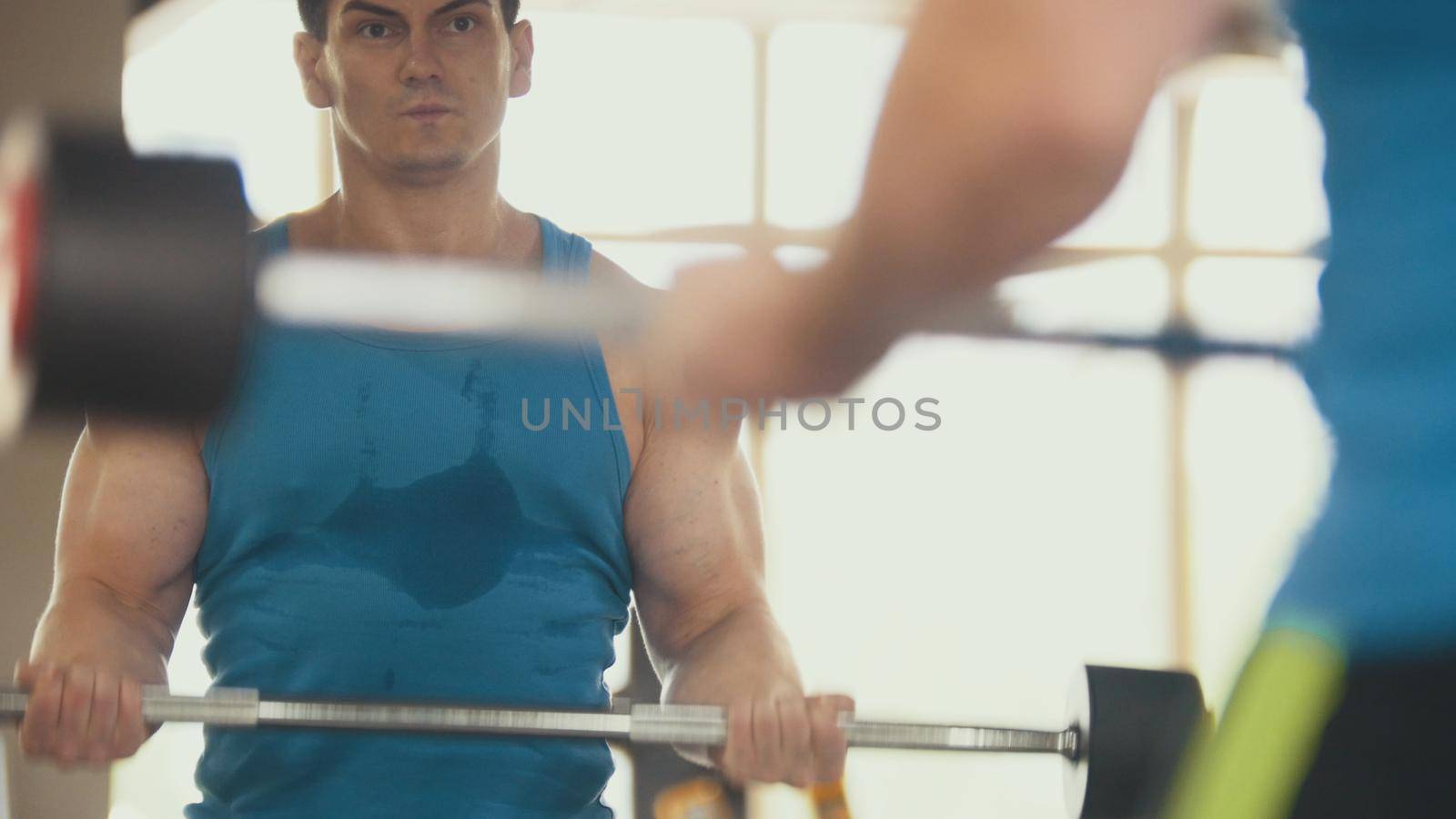 Bodybuilding in the gym - muscular man training his biceps near mirror, close up