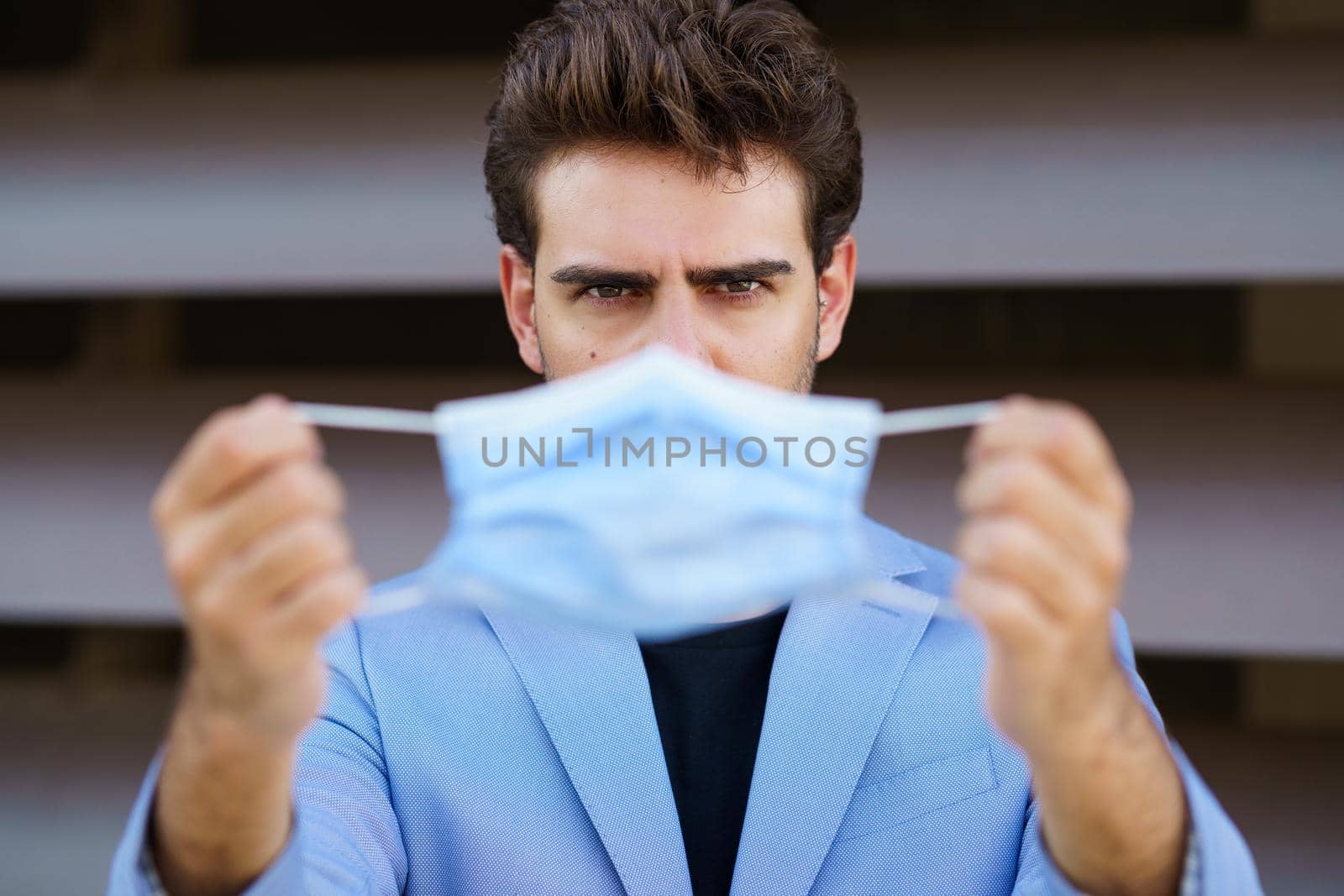 Businessman putting on a surgical mask to protect against the coronavirus. by javiindy