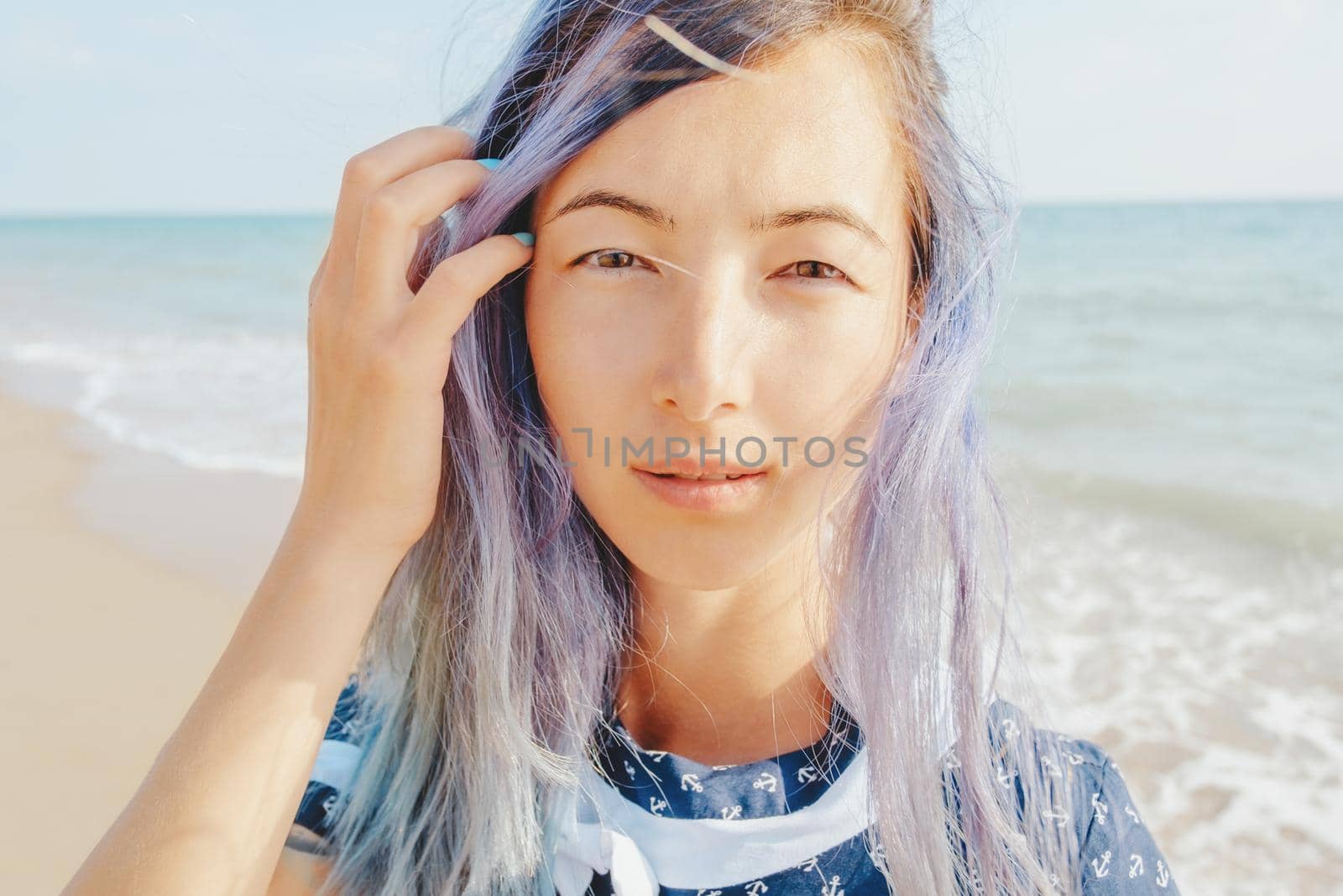 Portrait of beautiful girl with violet hair on background sea, looking at camera.