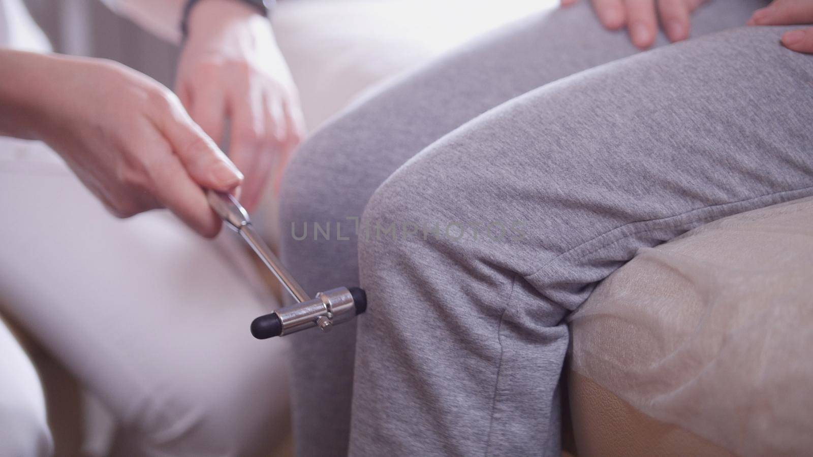 Doctor the neurologist examines the patient taps with a hammer on the knee, close up, health and medical concept