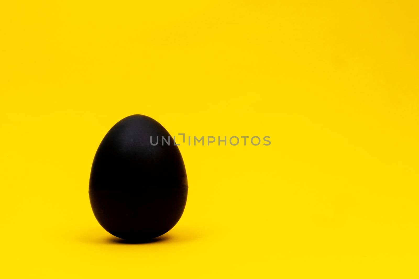 Black egg on yellow background by uveita