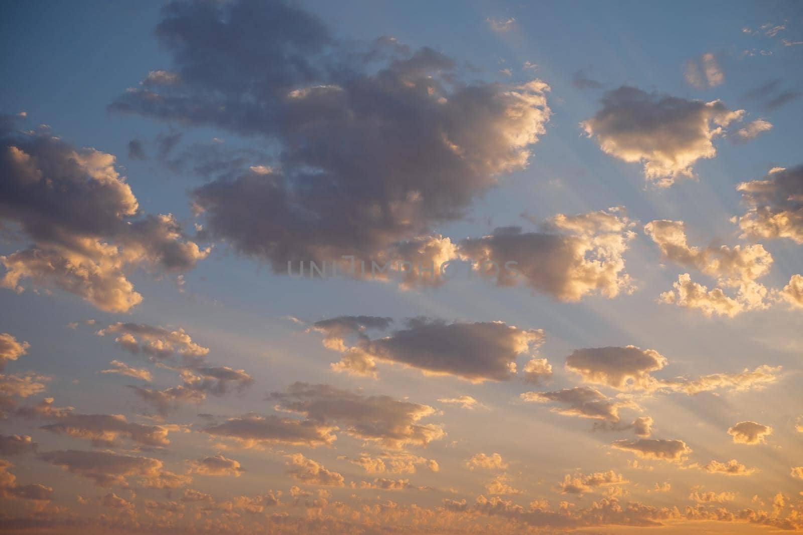 Beautiful sky background, sunset with sunbeams among small clouds.