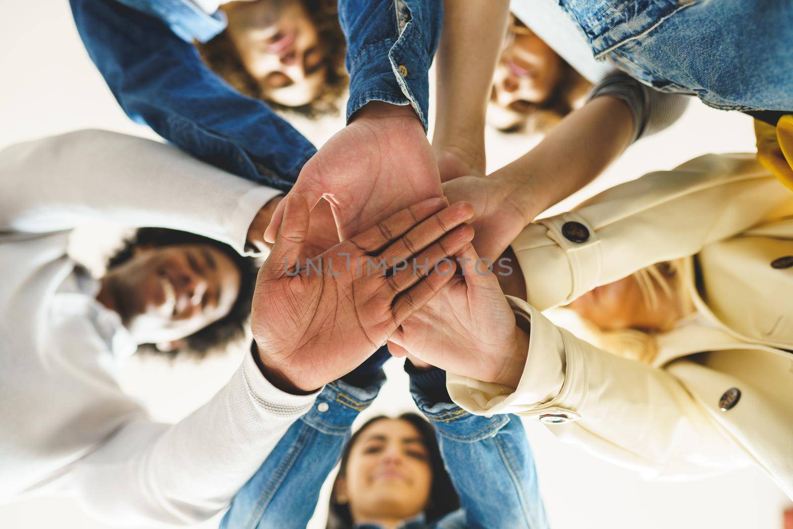 Hands of a multi-ethnic group of friends joined together as a sign of support and teamwork. by javiindy