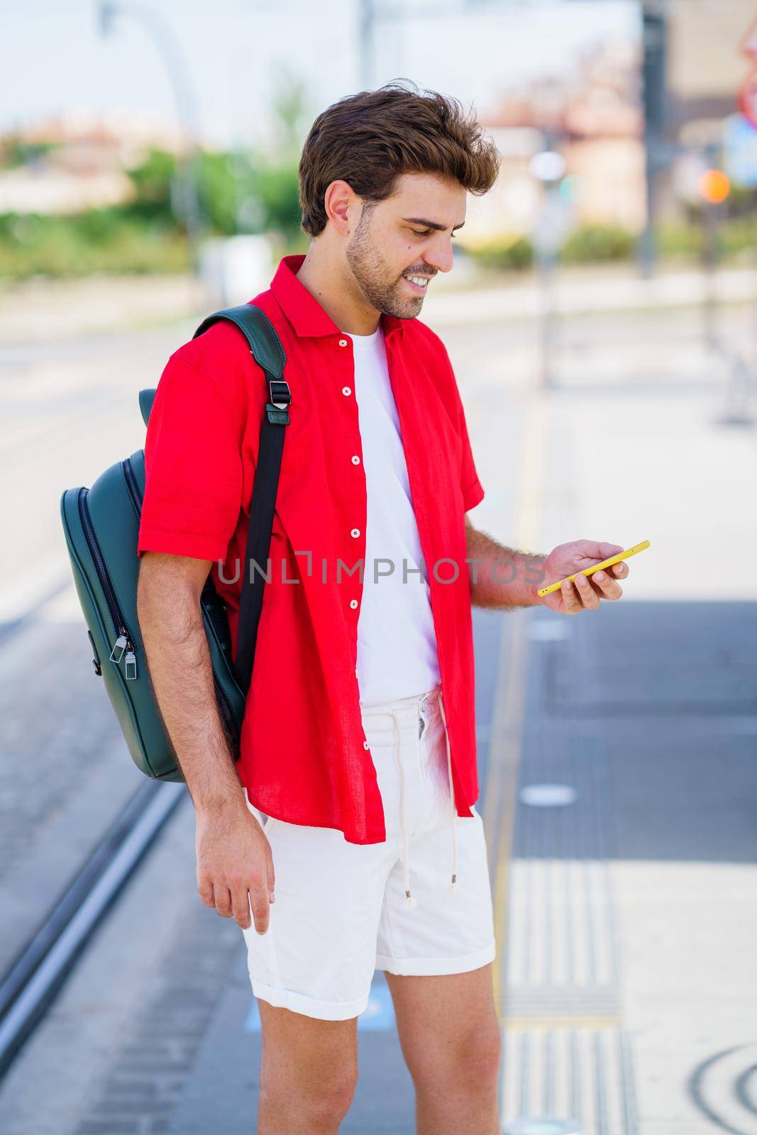 Young man waiting for a train at an outside station by javiindy