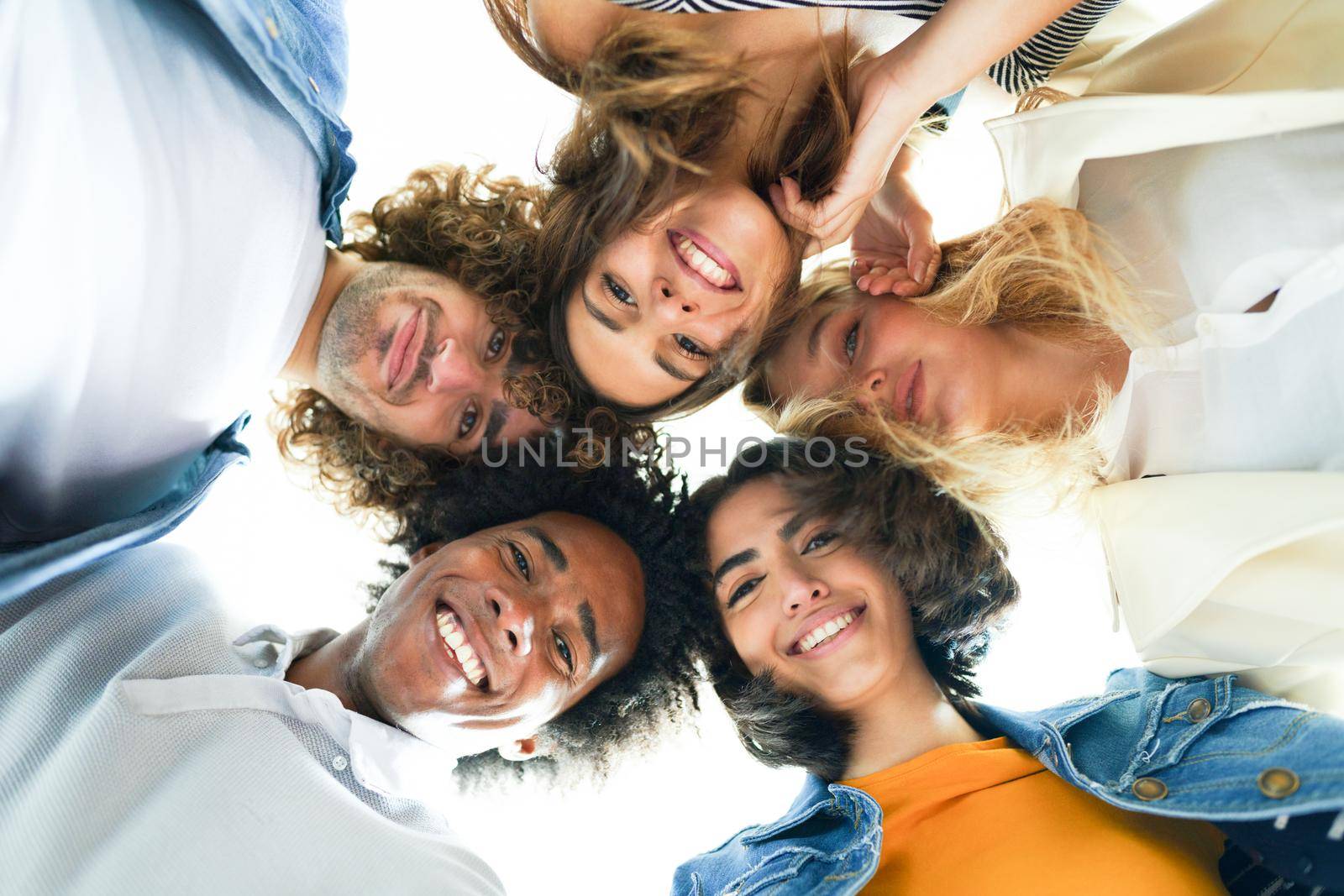 Multi-ethnic group of friends with their heads together in a circle outdoors