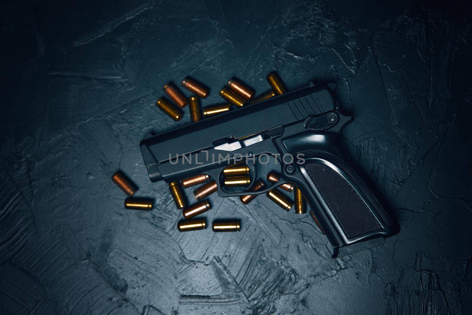 Flat lay of pistol and bullets. Firearms on dark background. Gun for defense or attack. Concept of crime ammunition and physical evidence. Weapons on concrete table.