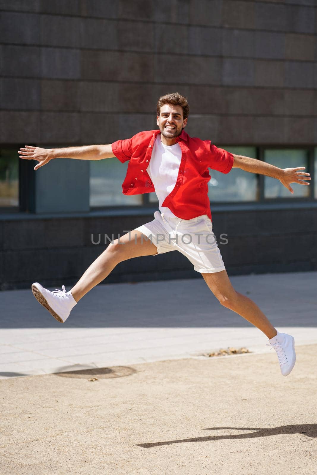Young man wearing casual clothes jumping in urban background.