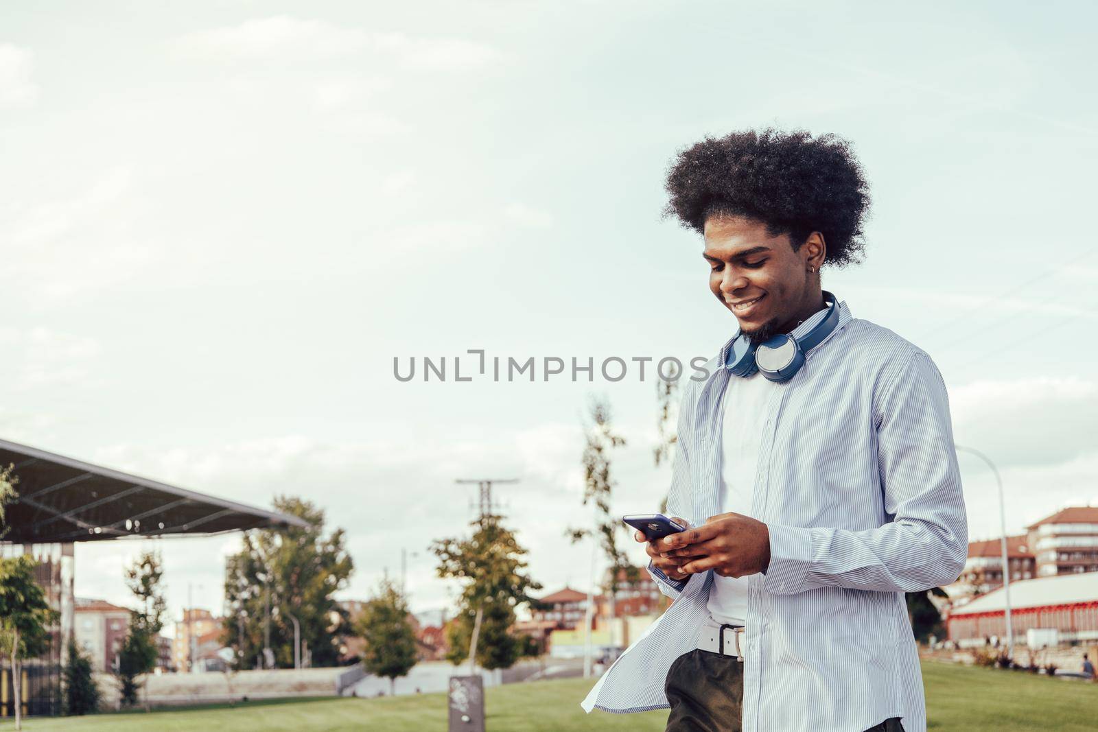 Portrait of afro guy using smartphone outdoors