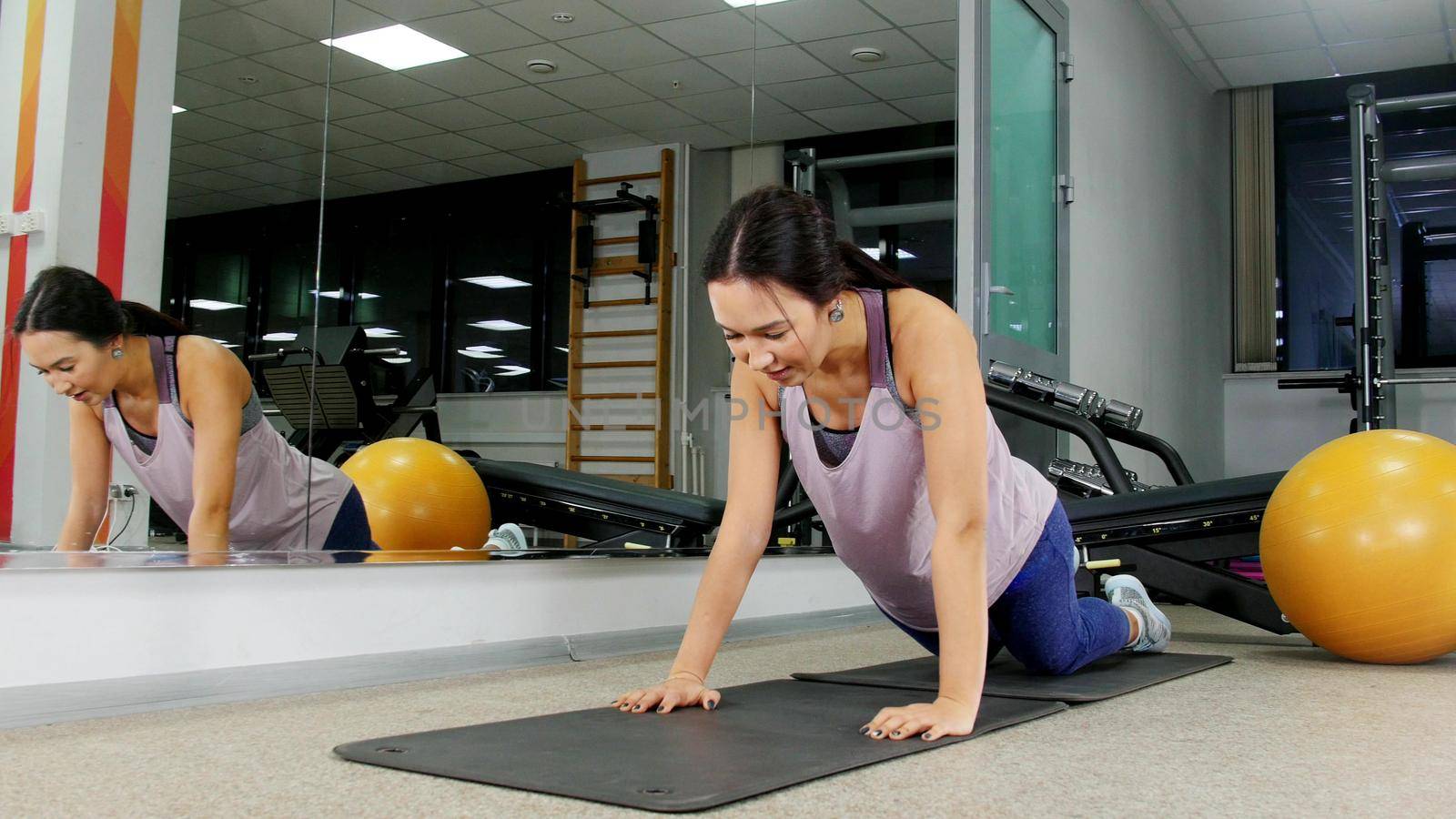 Training. A young woman in the gym doing push ups from the floor. Mid shot