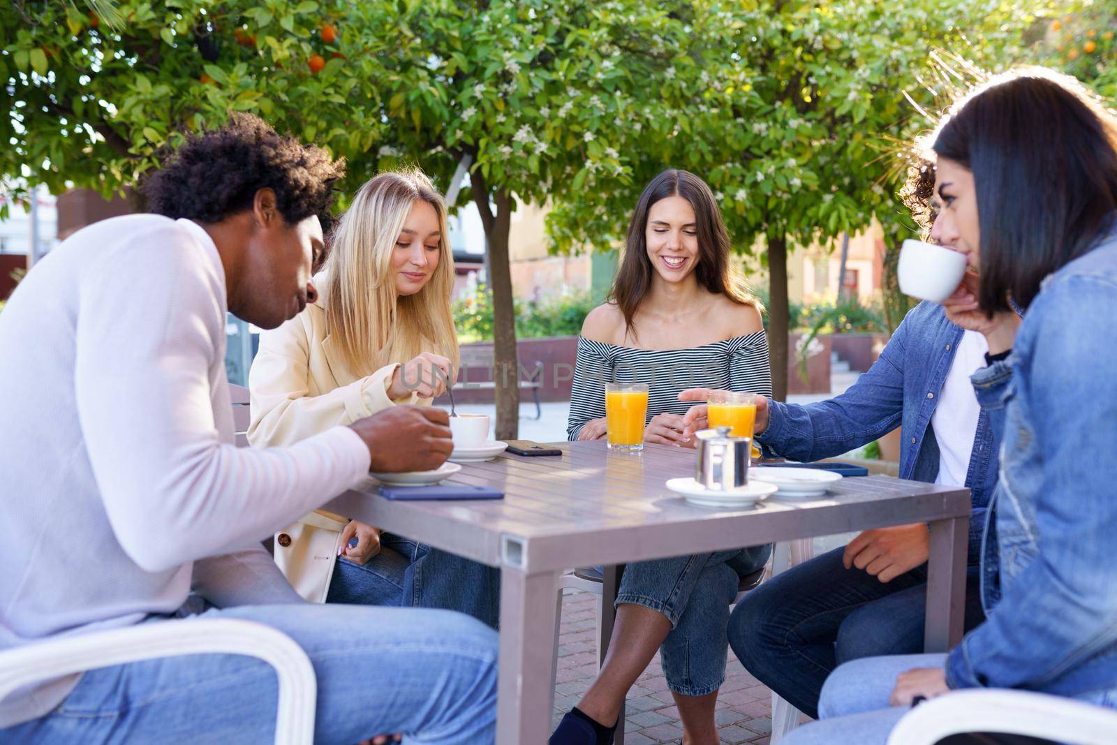 Multi-ethnic group of friends having a drink together in an outdoor bar. by javiindy