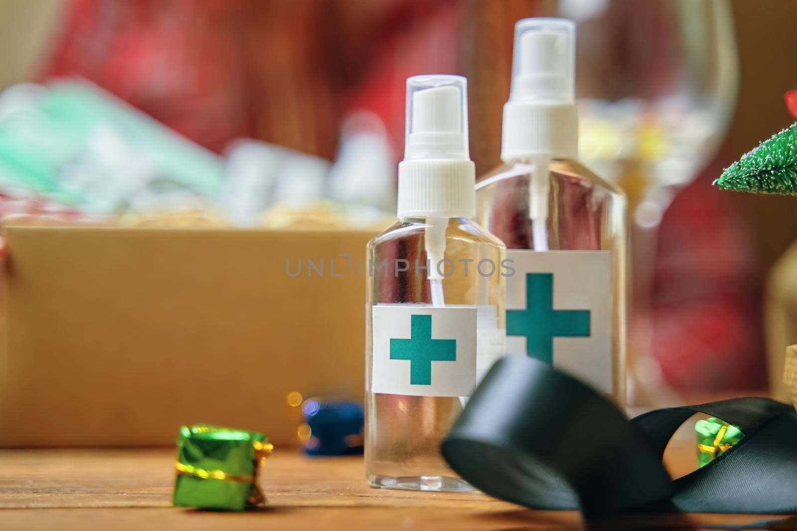 Alcohol antiseptics with blue cross logo on wooden table. Concept of hand hygiene and prevention from viruses and bacteria. Christmas decorations and sanitizers. New Year on quarantine.