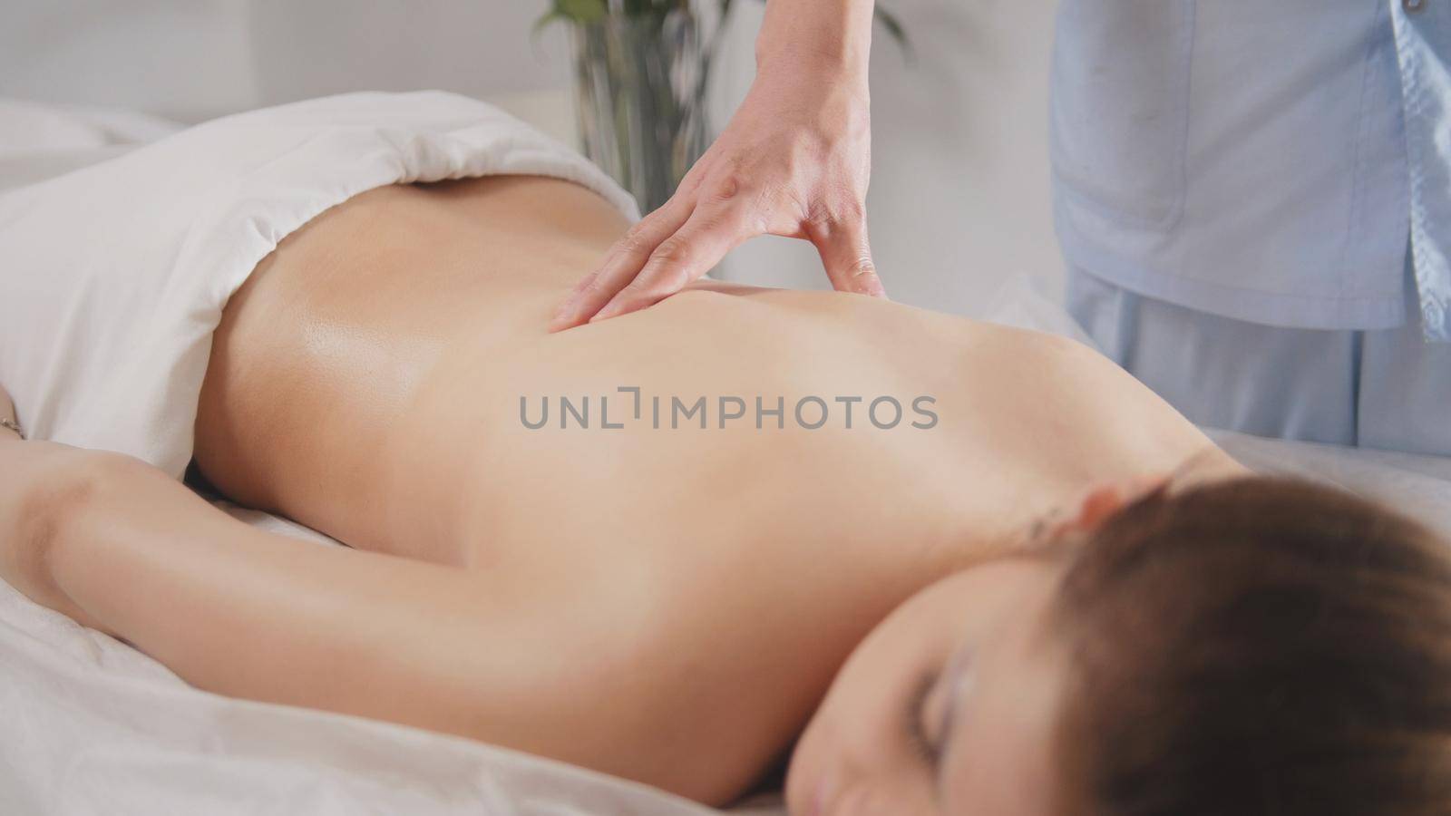 Young woman model receiving relaxing massage in spa room, close up view