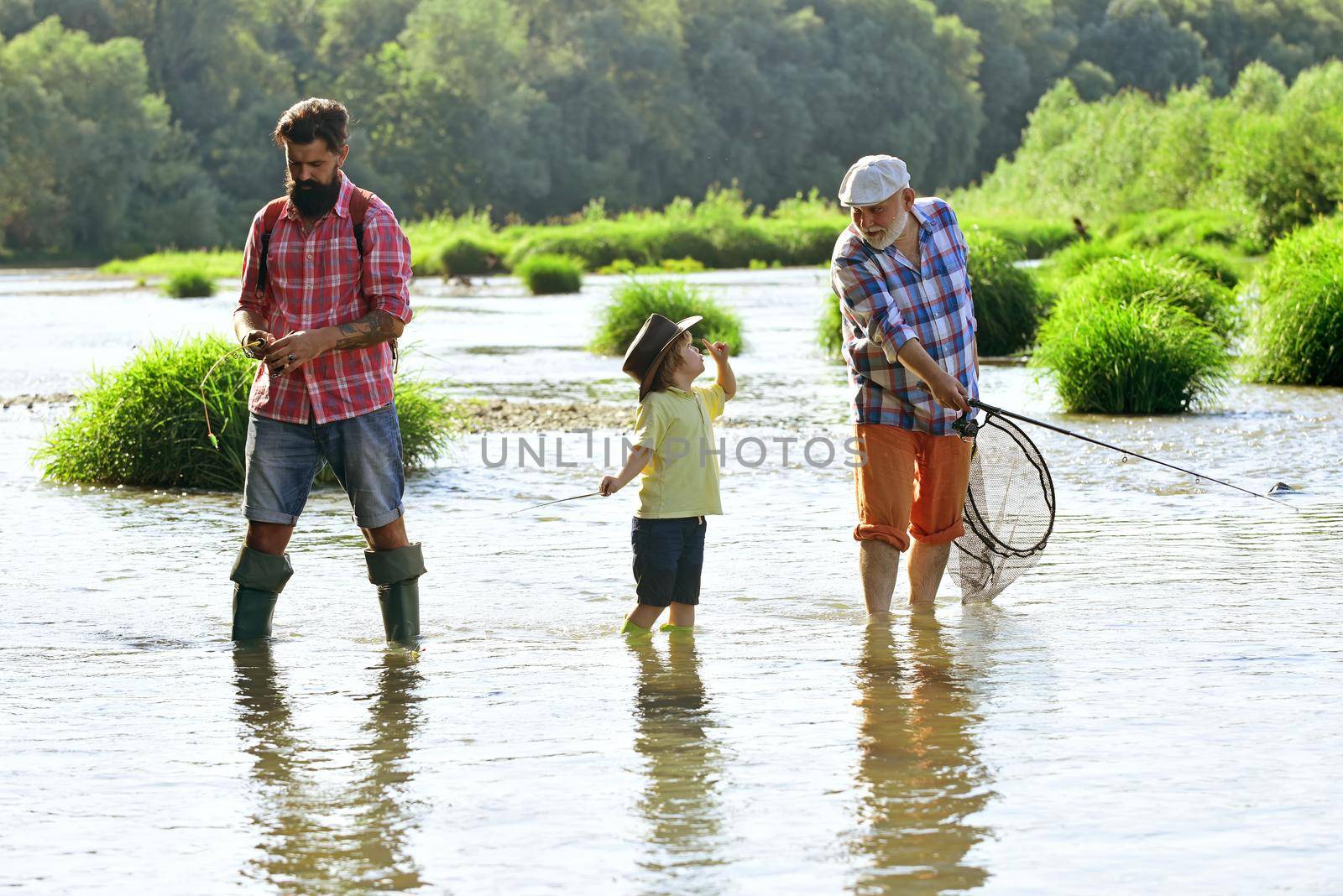 Happy grandfather, father and grandson with fishing rods on river berth. Fishing in river. Family bonding. Grandpa and grandson are fly fishing on river. Old and young