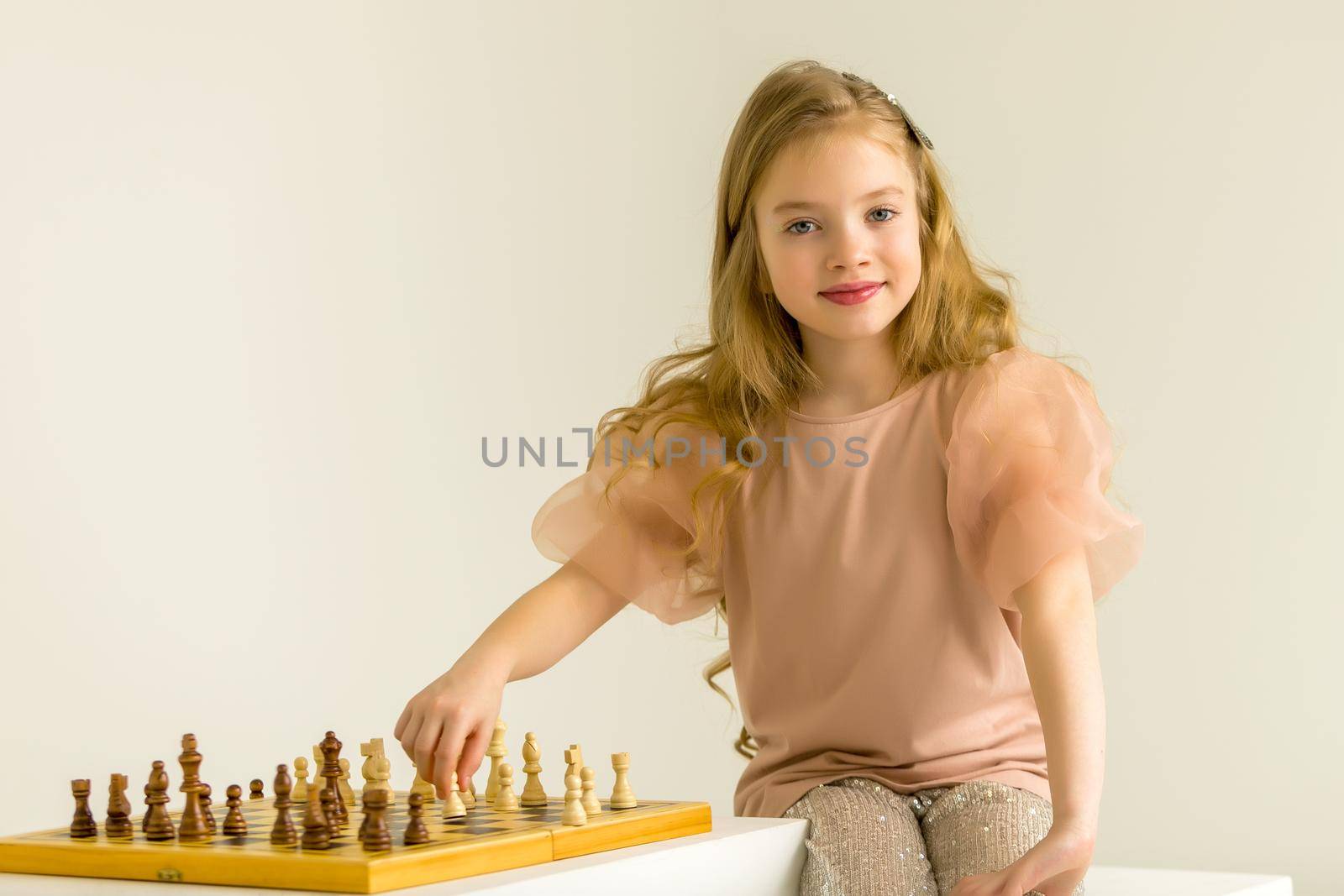 A little girl is playing chess. The concept of creative education of a child, training of thinking.
