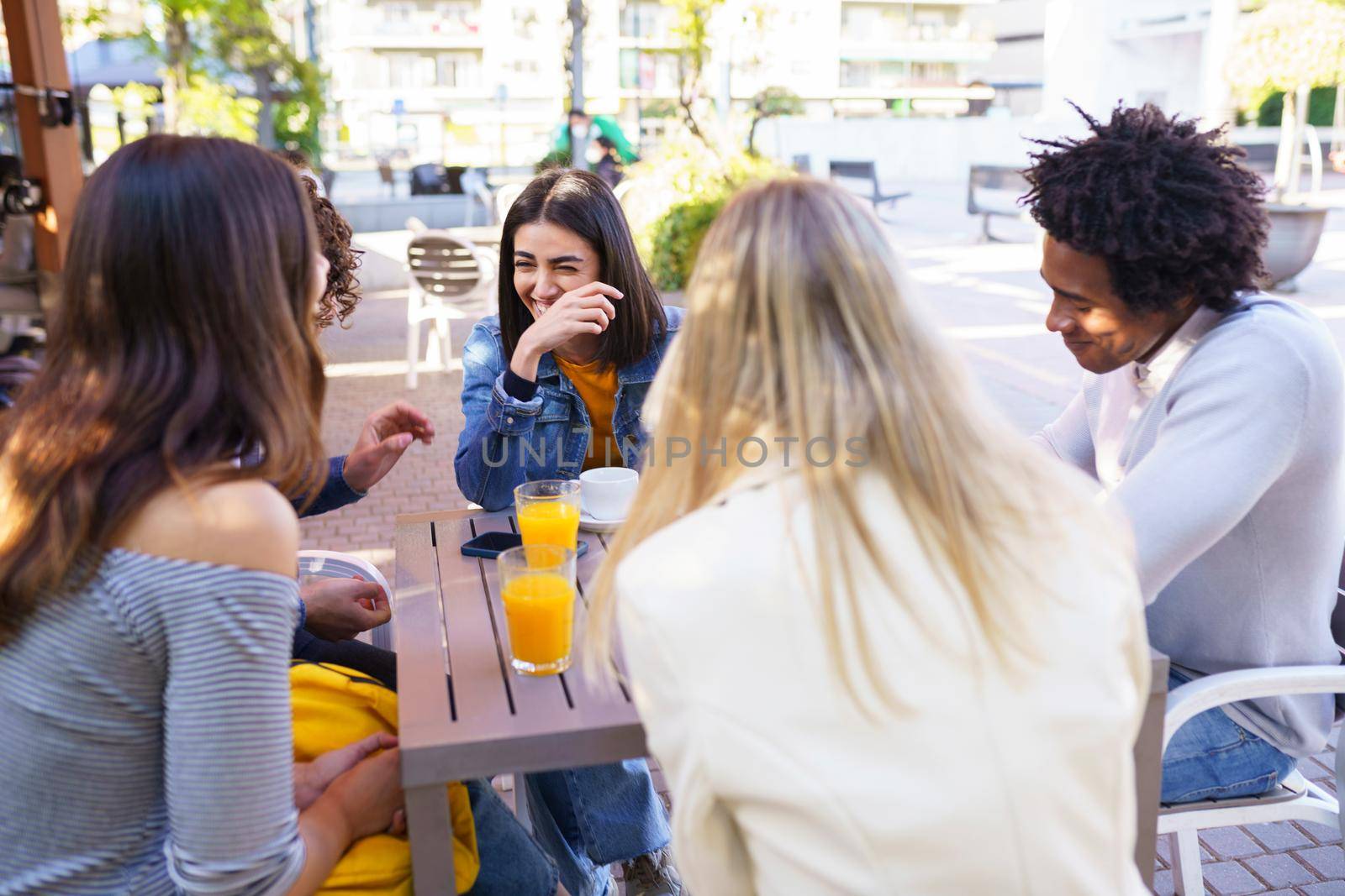 Multi-ethnic group of friends having a drink together in an outdoor bar. by javiindy