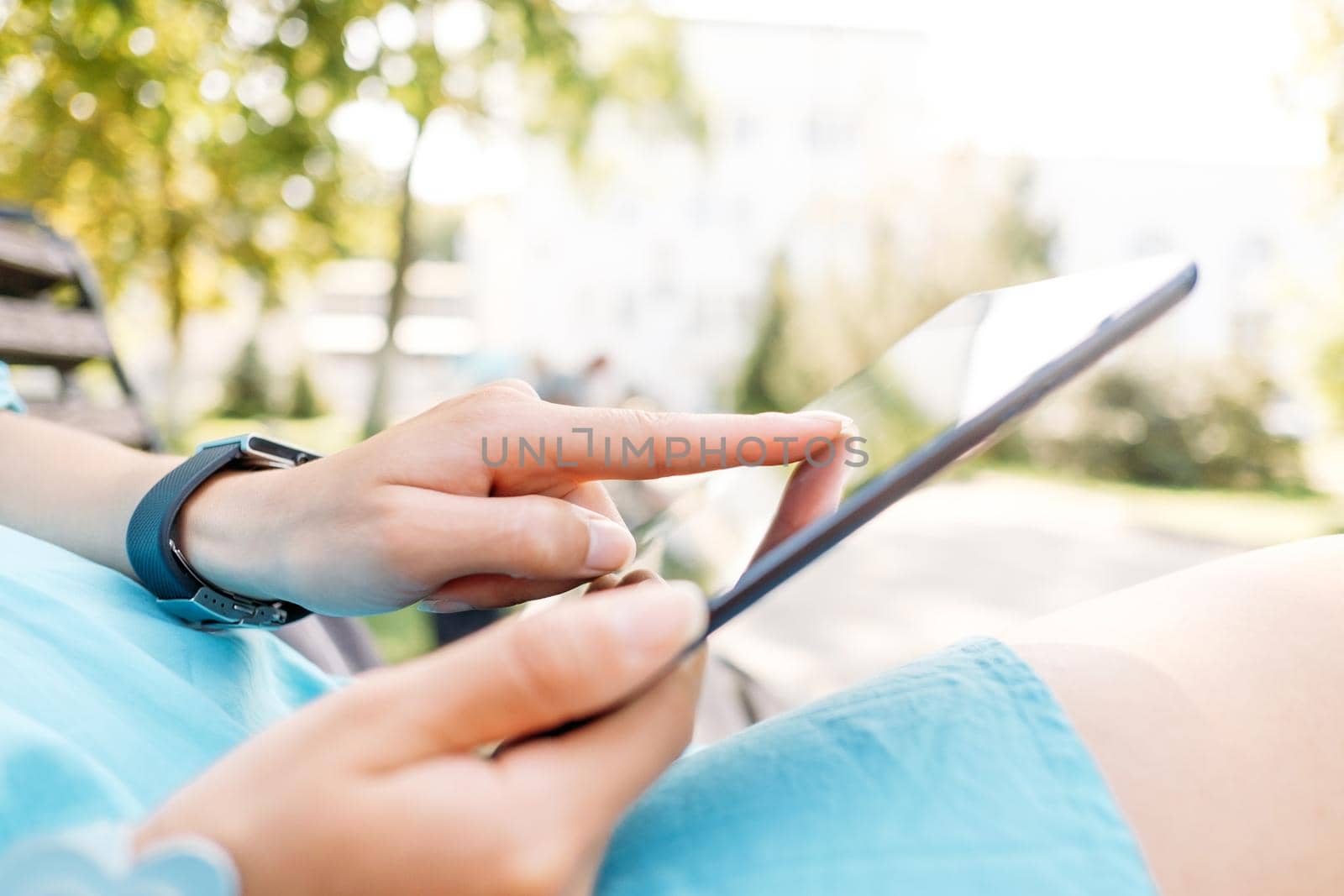 Close-up image of female hands with digital tablet in the park.