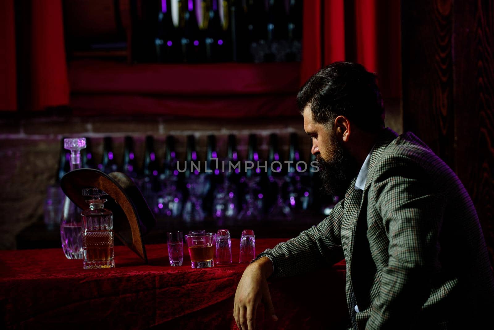 Portrait of a bearded man, with a glass of alcohol in his hands. Rest and relaxation in pub or bar