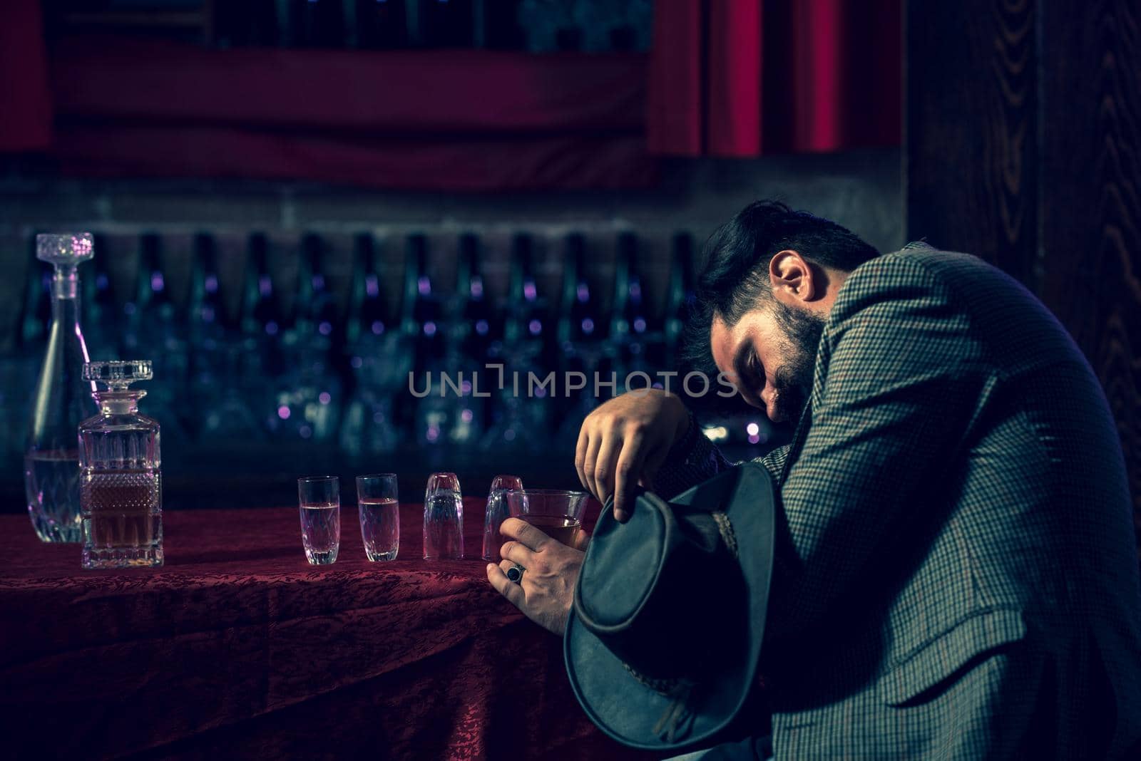 Drunk man holding glass. Client of beer pub sleeping and lying with his head on table. Concept of alcohol abuse and addiction. by Tverdokhlib