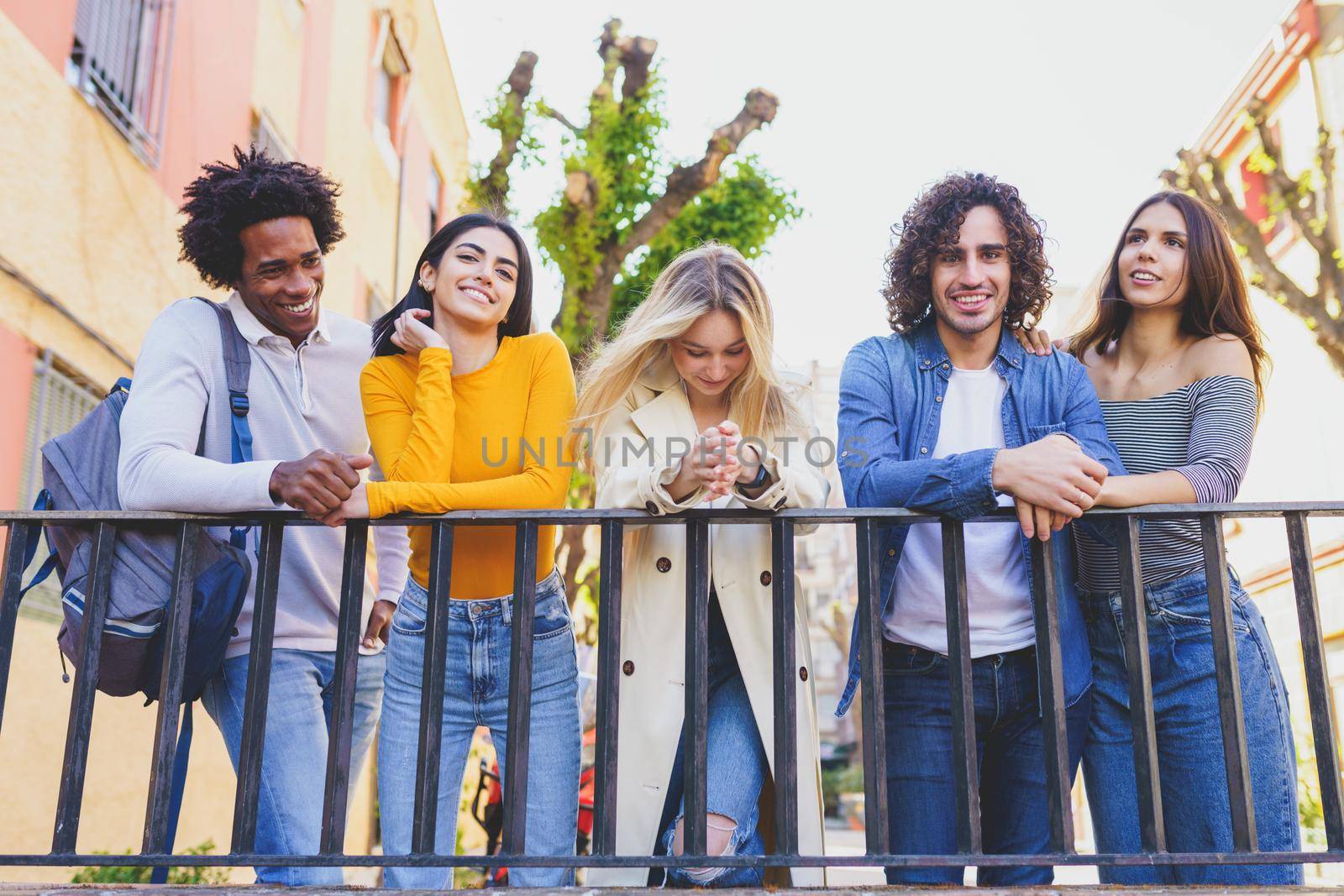 Multiracial group of young people talking together in the street. Students socializing.