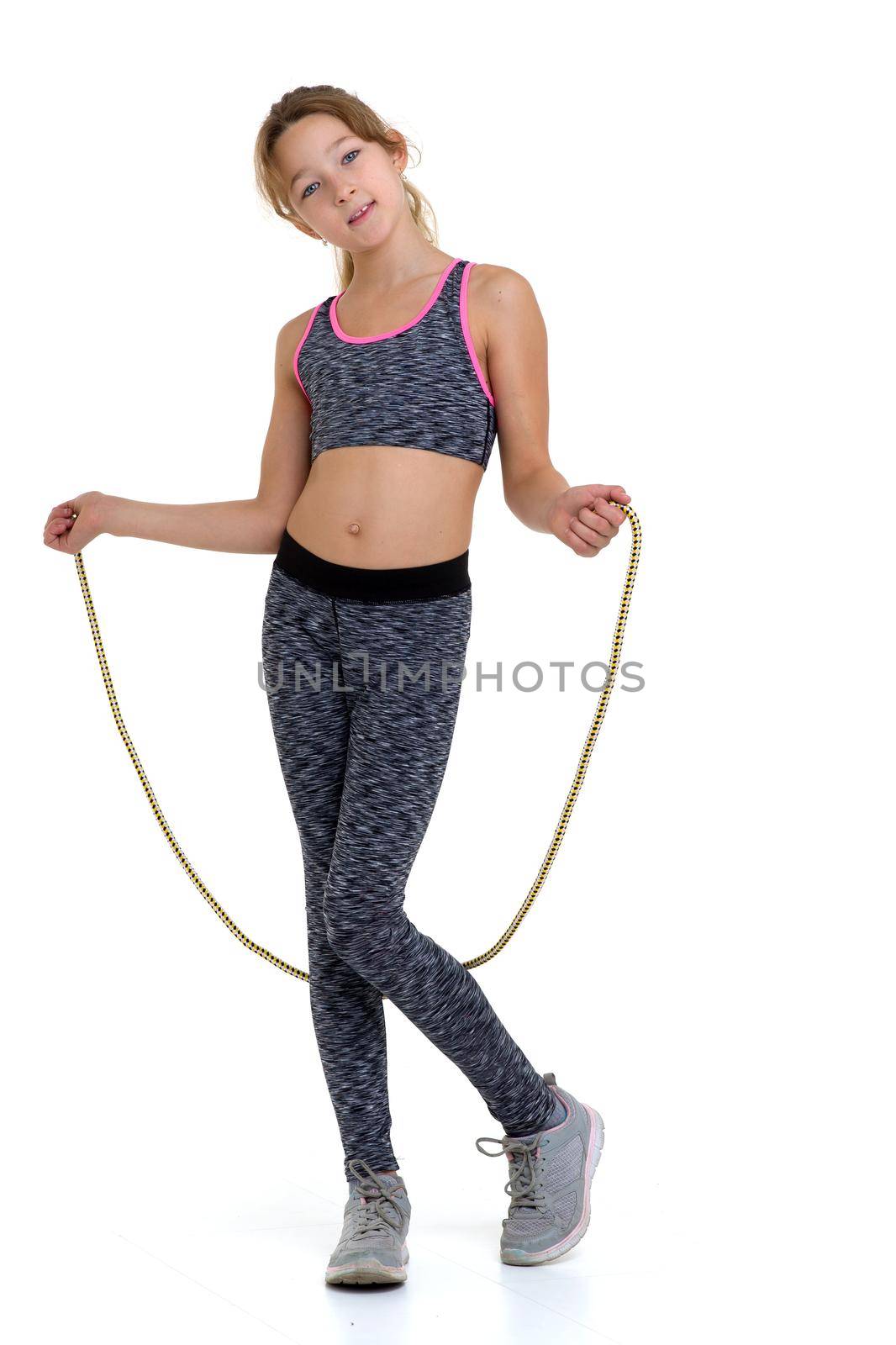 Teenage girl performing exercise with jumping rope. Cheerful girl gymnast wearing sportswear doing sports against white background. Active healthy lifestyle concept