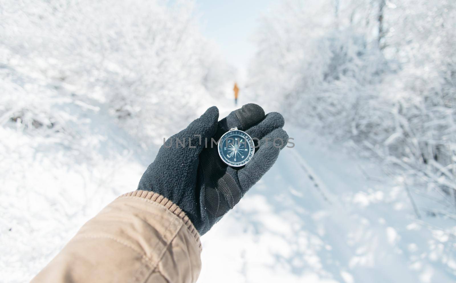 Man searching direction with compass in winter snowy forest, point of view.