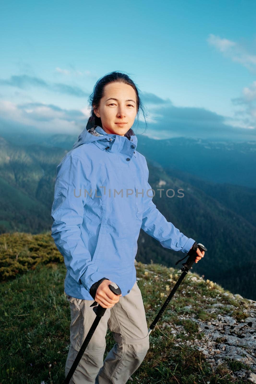 Outdoor explorer young woman standing in the mountains and looking at camera.