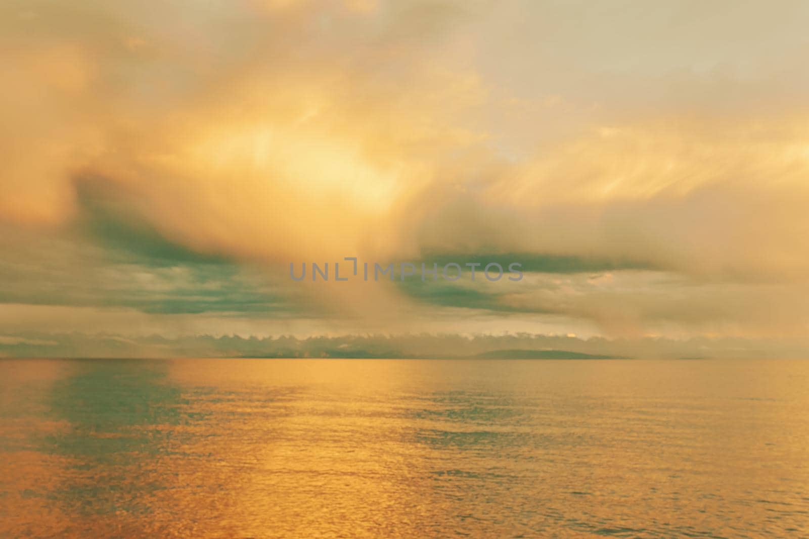 Summer landscape. Beautiful clouds over sea. Sunlight through clouds. Beach with trees on horizon. Travel background.