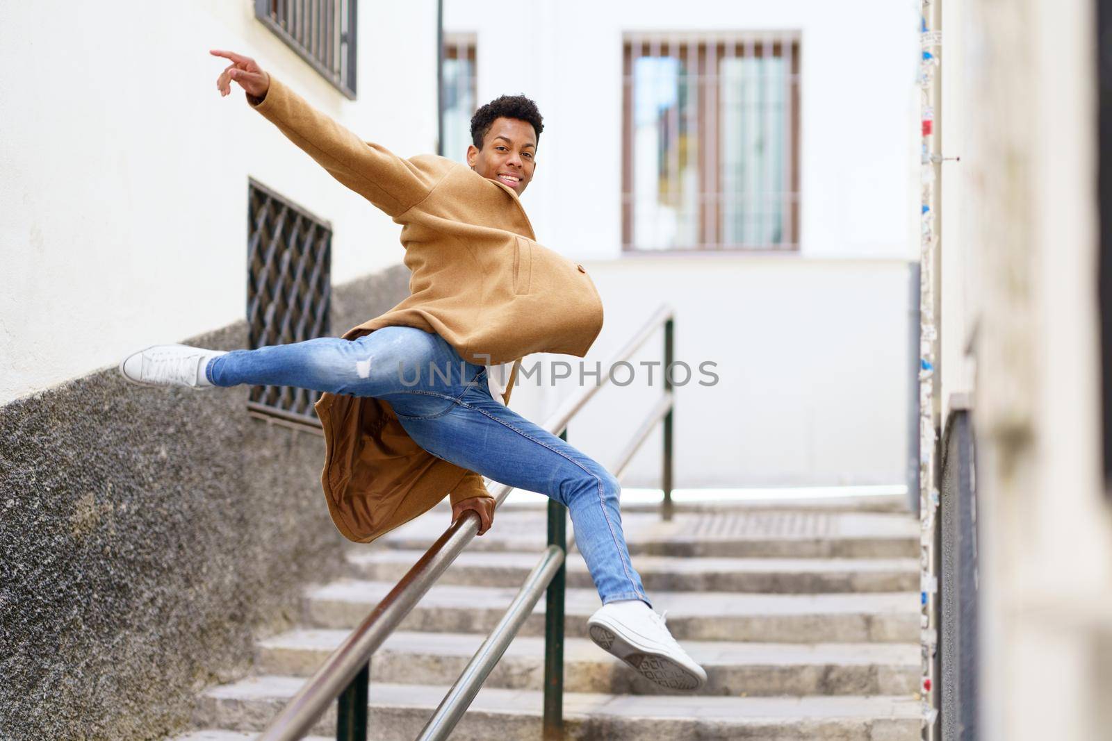 Cuban man jumping for joy over a handrail in the street. Young black guy.