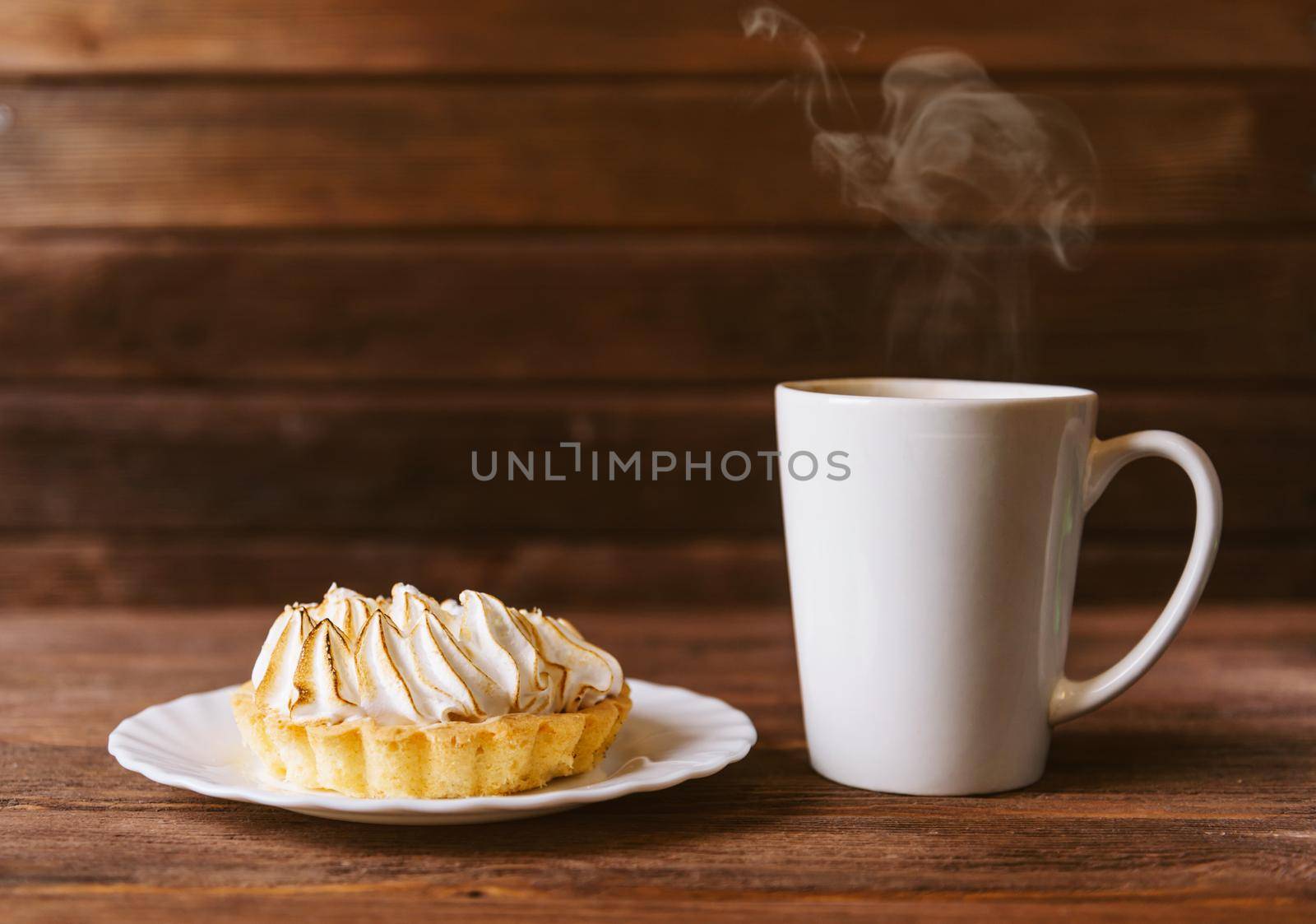 Cupcake and cup of hot drink on a wooden background.