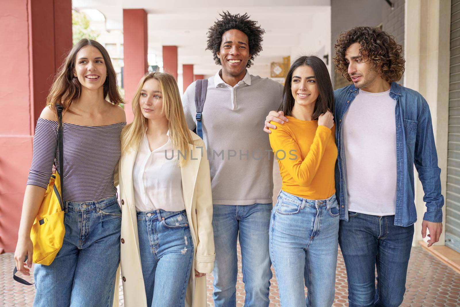 Multi-ethnic group of friends walking together on the street while chatting and having fun.