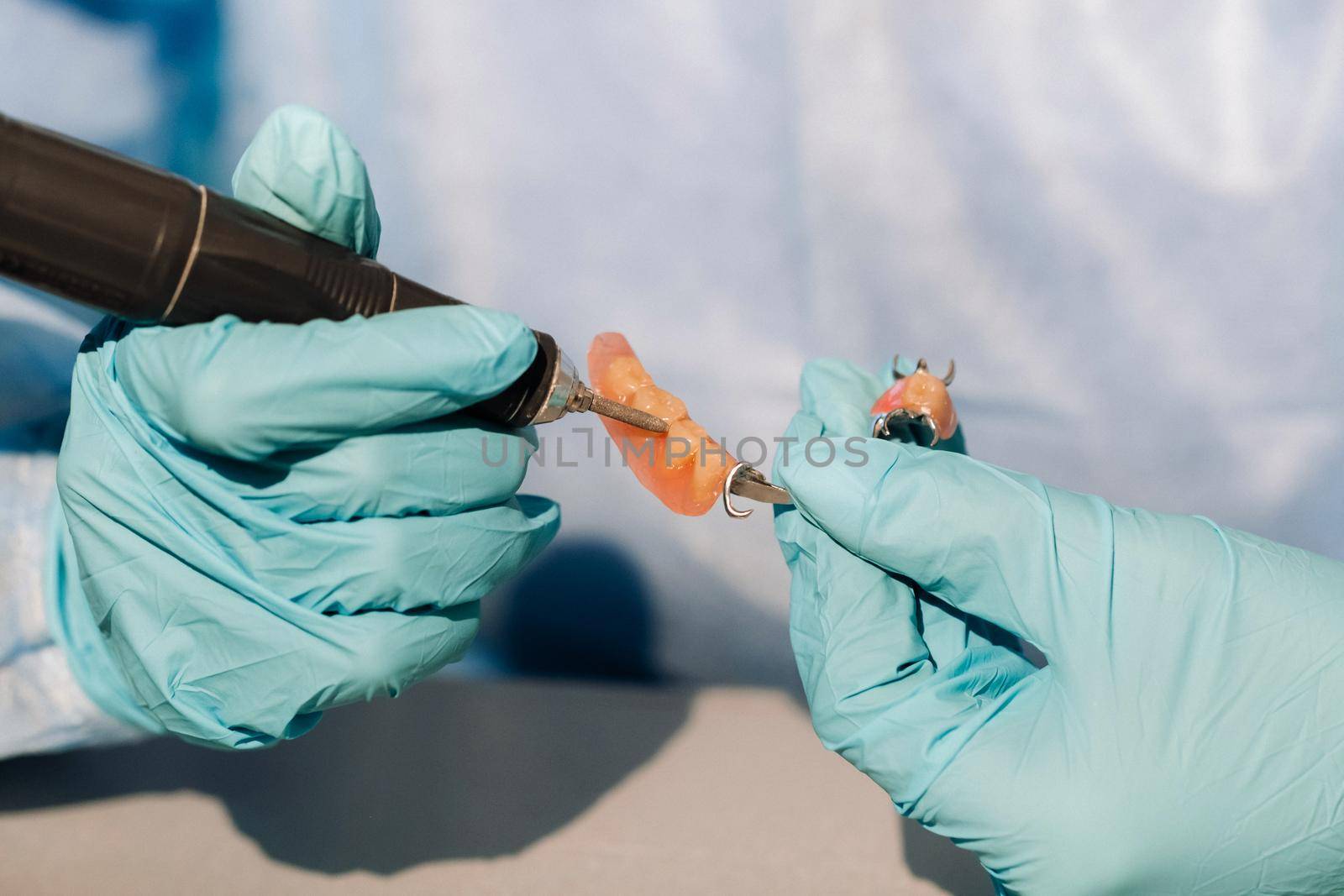 close-up of a gloved dental technician working on a prosthetic tooth in his lab.