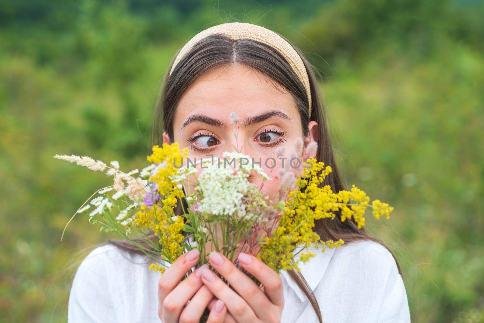 Funny spring young woman outdoor. Beautiful teen girl in a field of white flowers. Fun face emotions. Girl with a bouquet of wildflowers